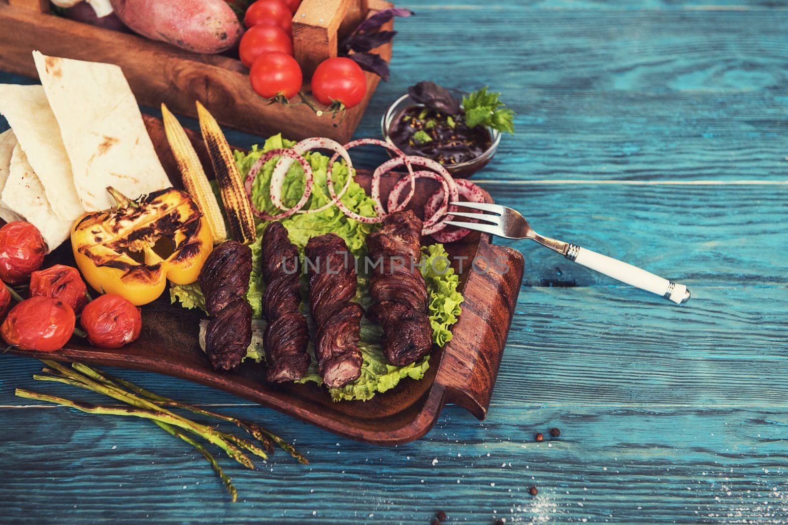 Grilled lamb meat with vegetable on a blue wooden background