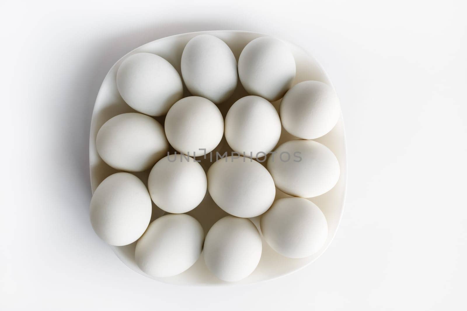 White eggs on a plate on a light background.
