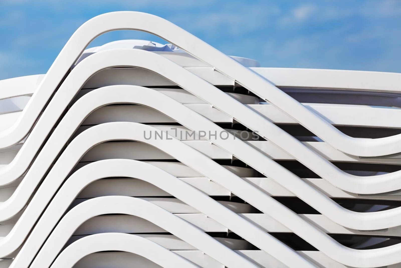 Pile of white plastic deck chairs, Folded stack of beach loungers. Abstract background or texture
