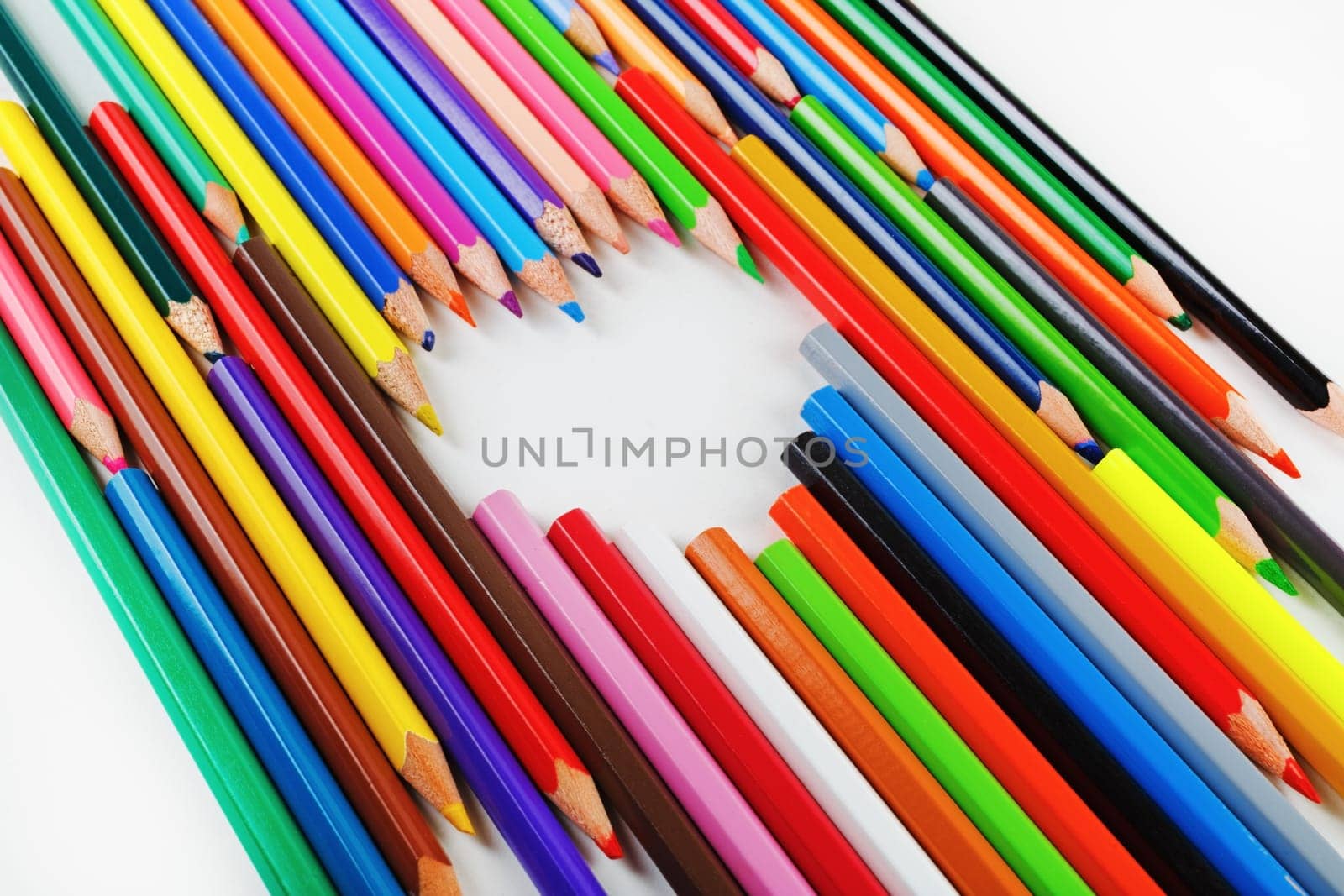 Bright colored pencils laid out in a heart shape. Pencils lying on a flat surface.