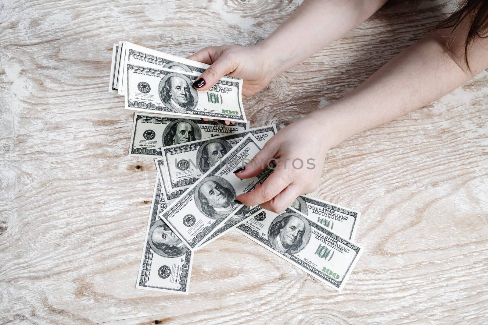 Woman counting money. Dollars in woman's hands. Many one hundred dollar bills in hands.