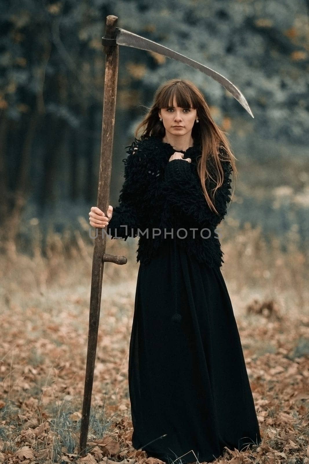 Closeup picture of pretty serious beautiful girl with long hair in black clothes with braid on dark forest background. Serious mystical girl with serious face and braid on Halloween party.