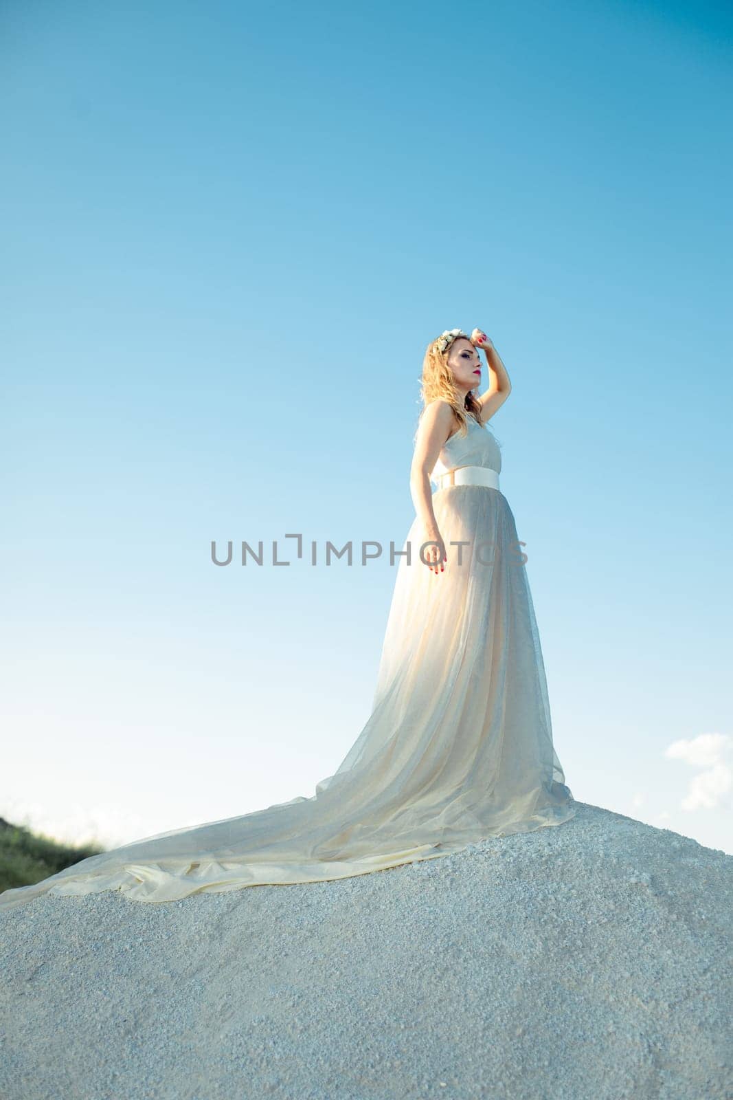 Beautiful smiling thinking girl with long white dress with loop standing outdoors in summer