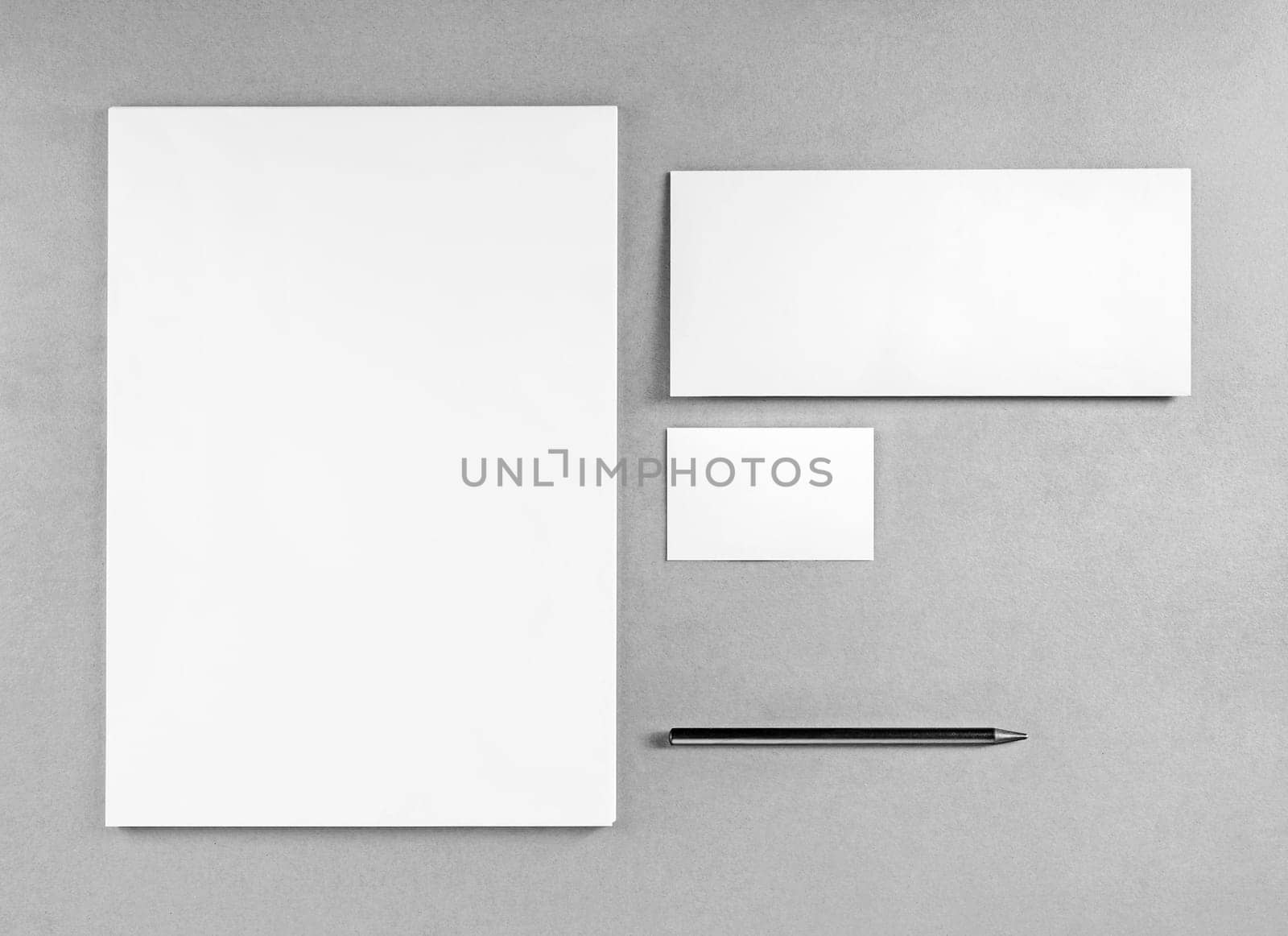 Blank stationery template for placing your design. Photo of blank stationery set. Blank letterhead, business cards, envelope and pencil. Mockup for branding identity. Top view. Grayscale image.