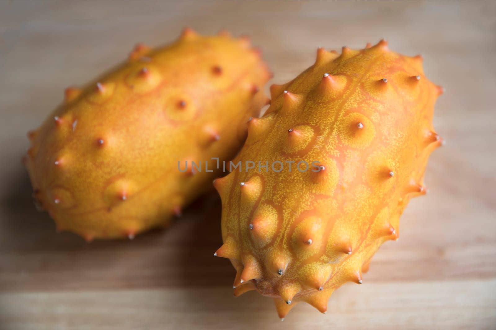 Two whole kiwano fruits on wodden surface