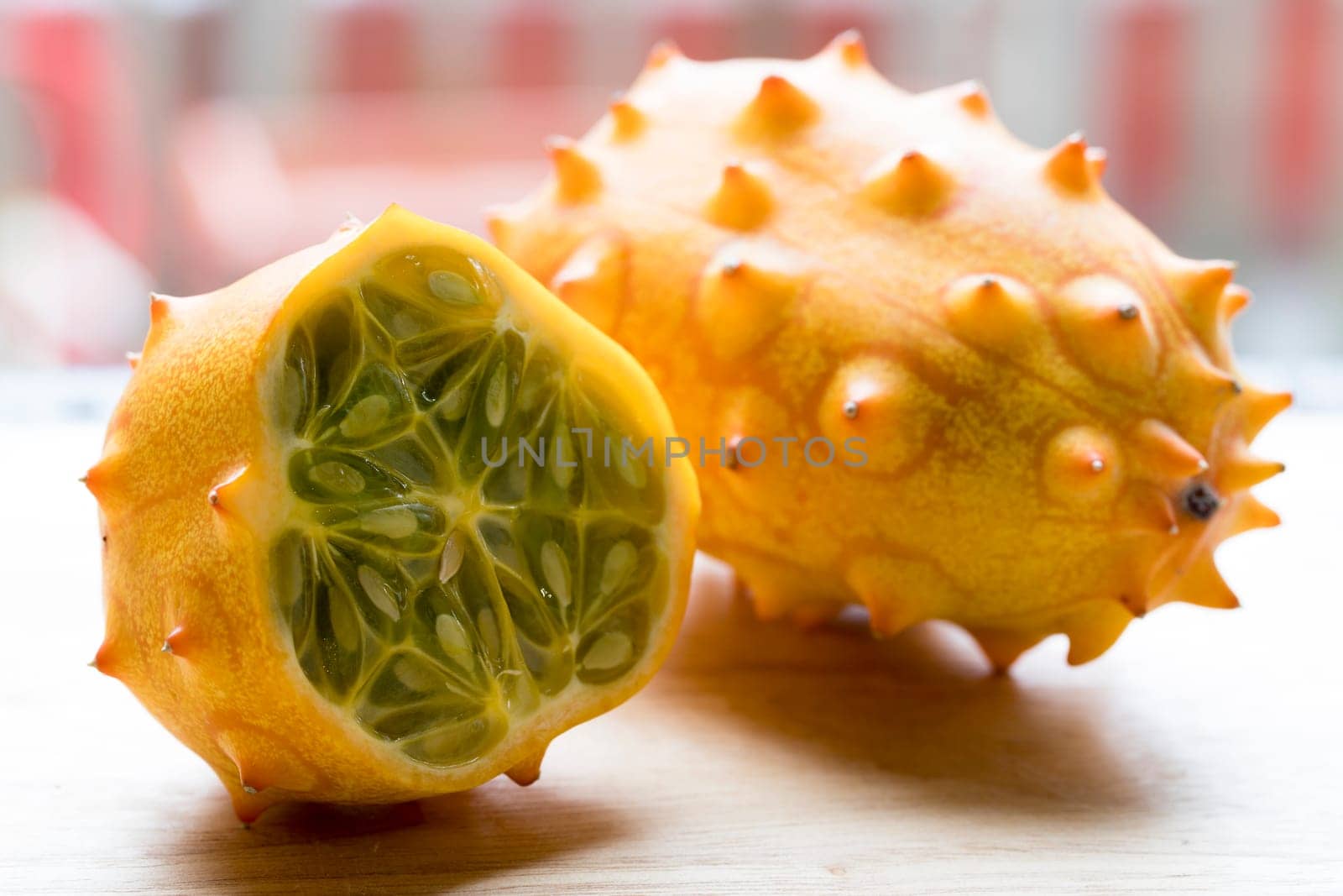 Whole and cut kiwano fruit on cutting board.