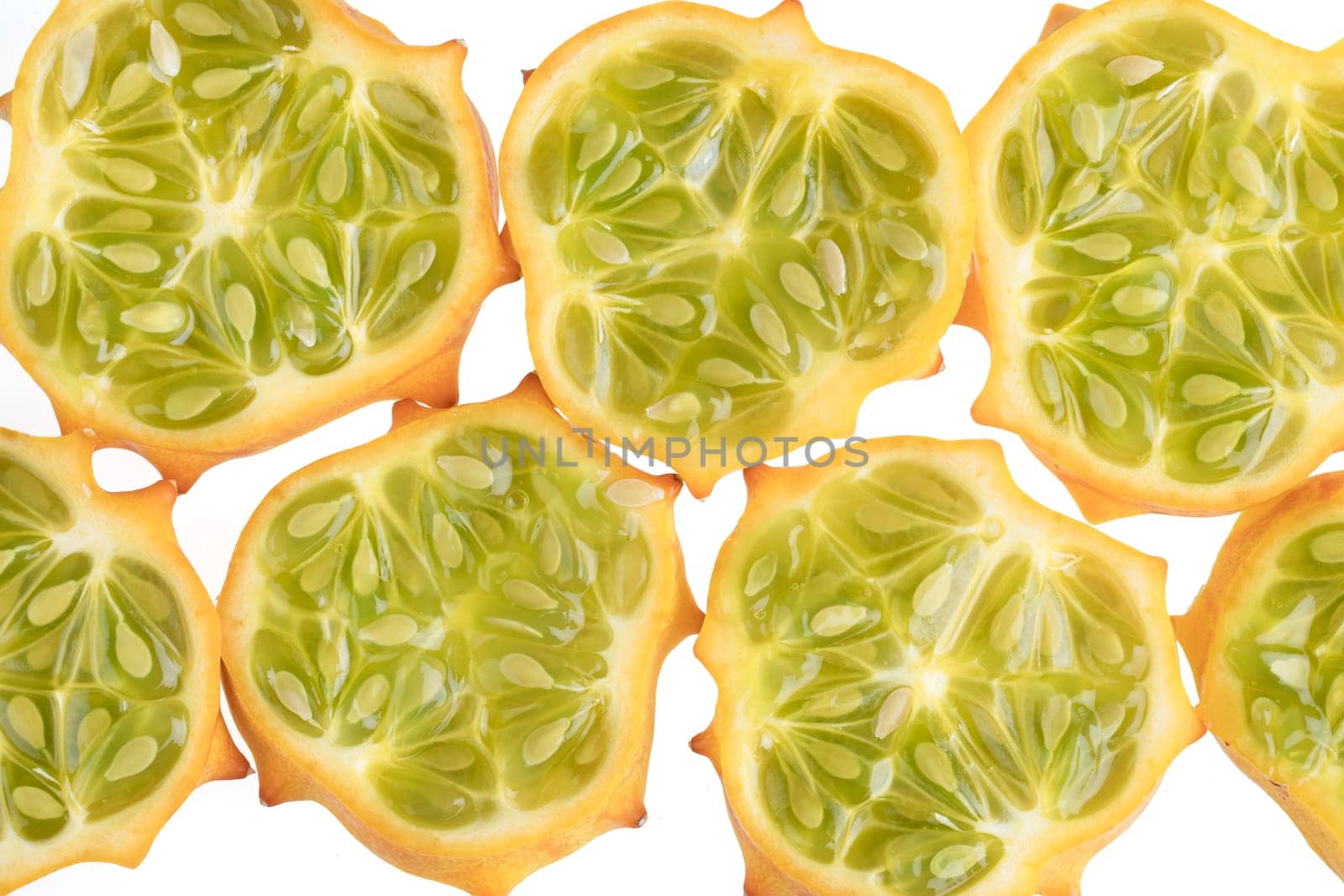 Several slices of kiwano fruit on white.