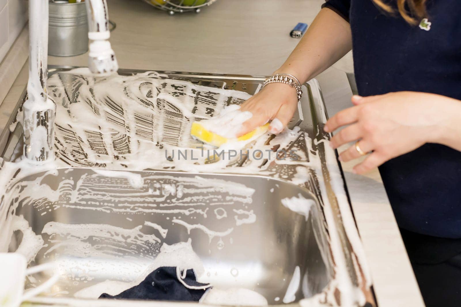 a woman doing chores in kitchen at home, cleaning sink and faucet