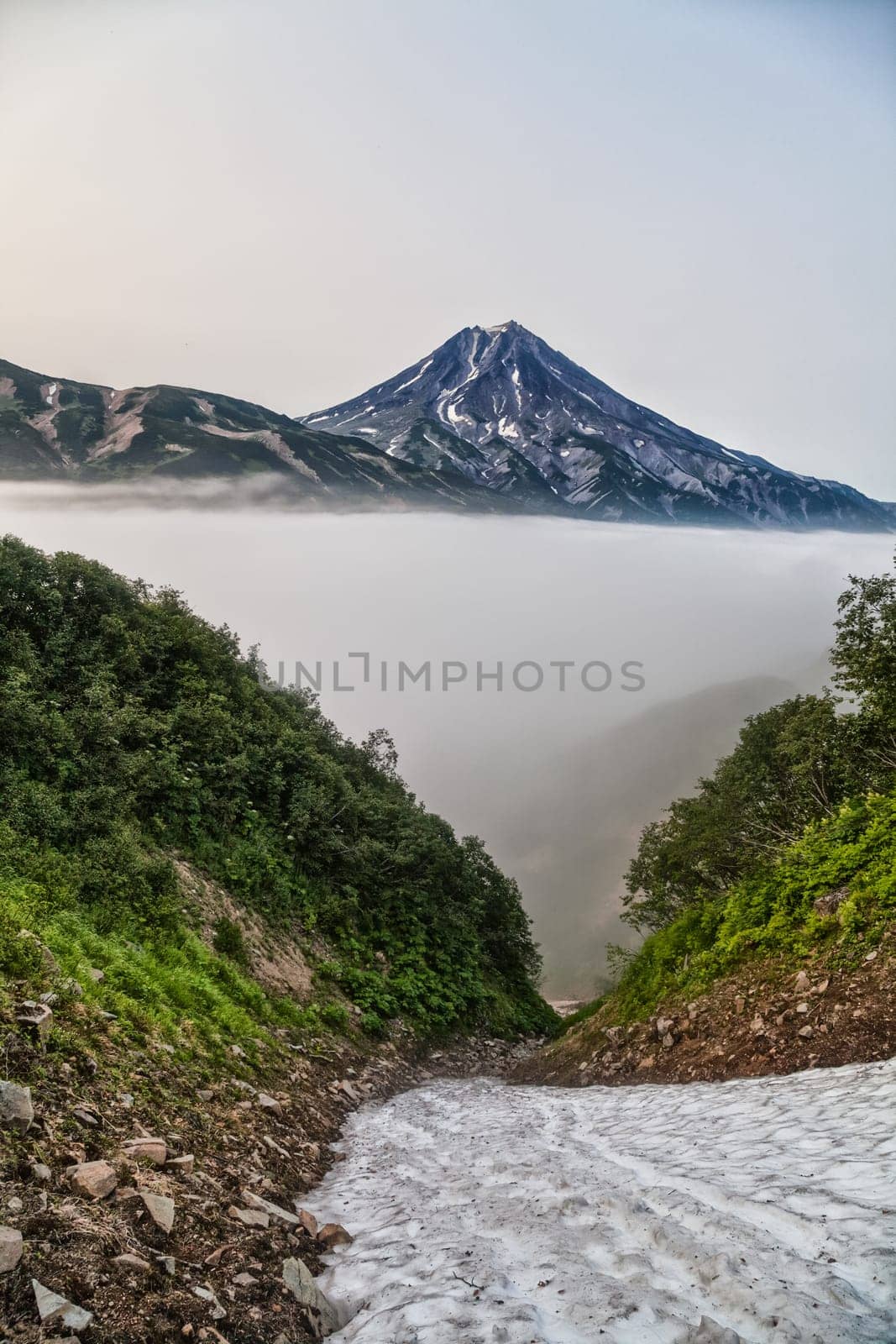 Mountains and volcanoes. Beautiful landscape of Kamchatka Peninsula: summer panoramic view of Mountain Range Vachkazhets, mountain lake and clouds in blue sky on sunny day. Eurasia, Russian Far East, Kamchatka Region.