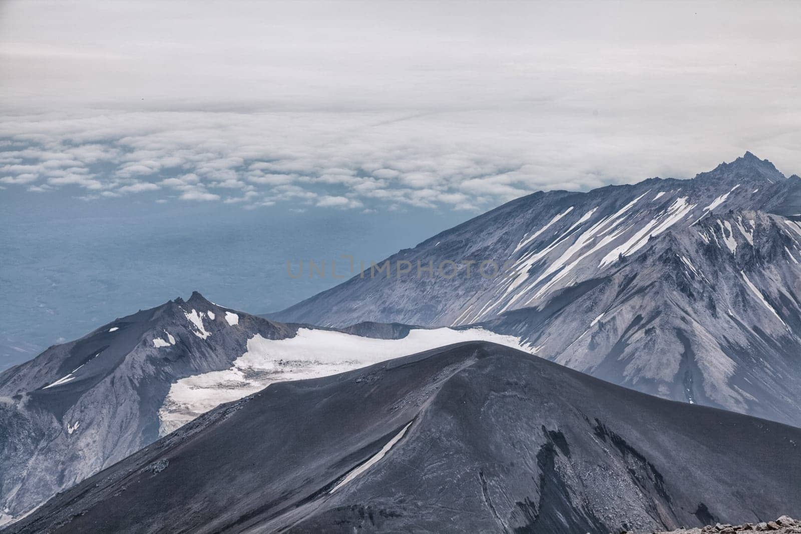 Mountains and volcanoes. Beautiful landscape of Kamchatka Peninsula: summer panoramic view of Mountain Range Vachkazhets, mountain lake and clouds in blue sky on sunny day. Eurasia, Russian Far East, Kamchatka Region.