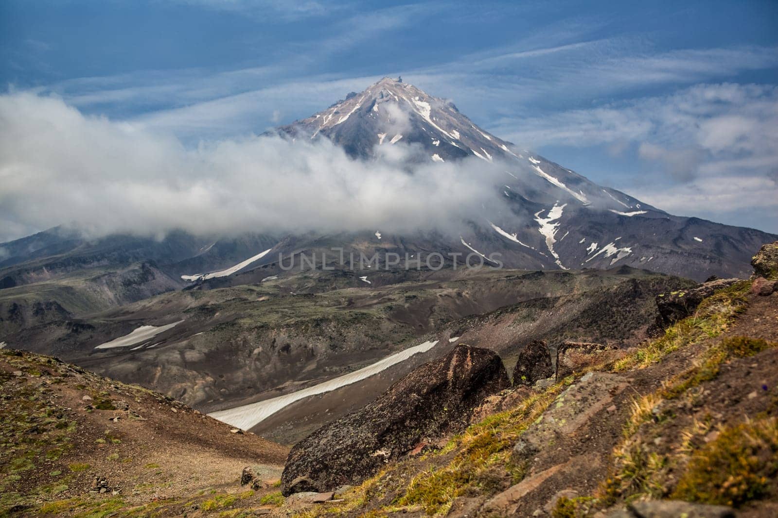 Mountains and volcanoes. Beautiful landscape of Kamchatka Peninsula: summer panoramic view of Mountain Range Vachkazhets, mountain lake and clouds in blue sky on sunny day. Eurasia, Russian Far East, Kamchatka Region.