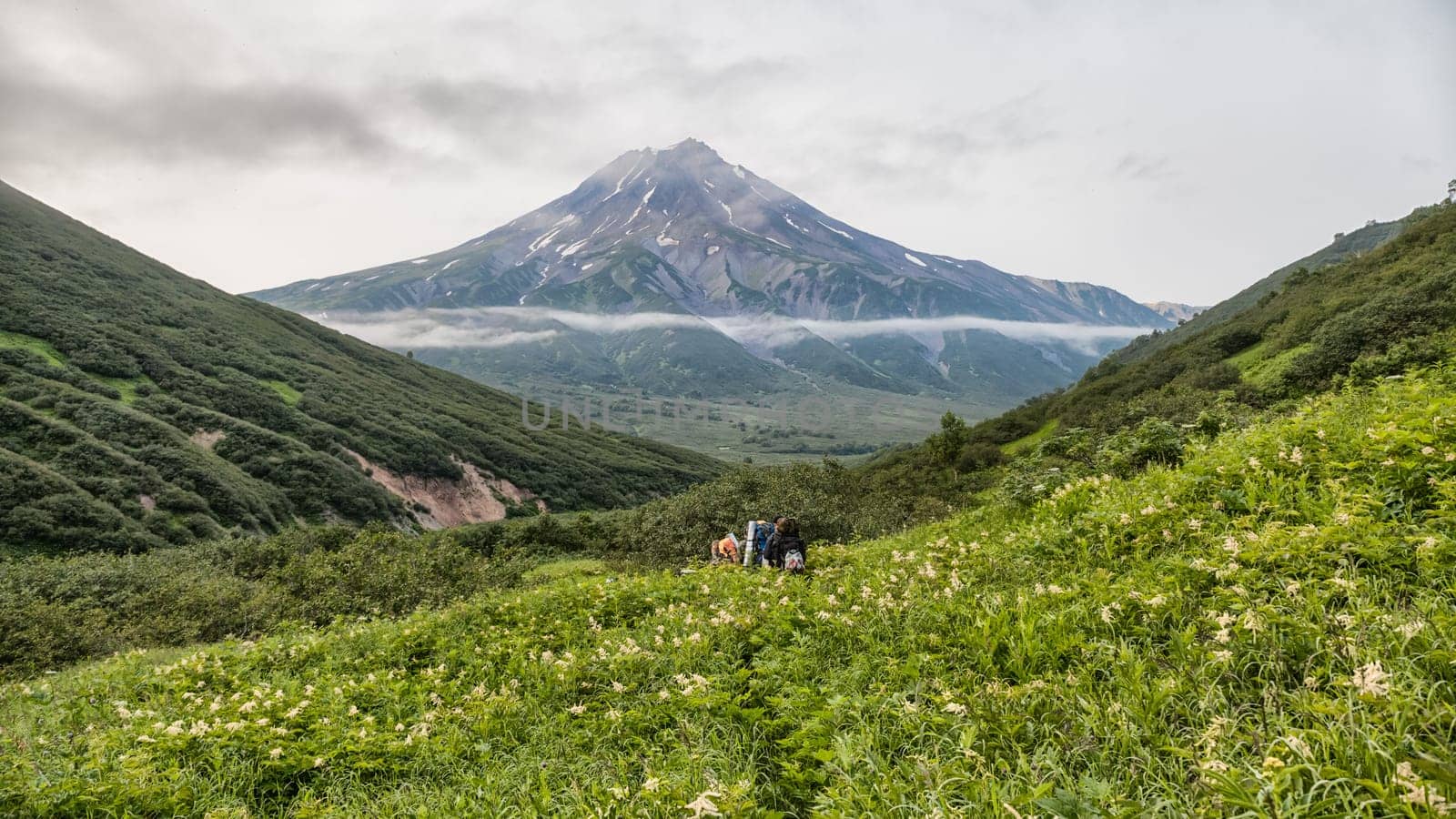 Mountains and volcanoes. Beautiful landscape of Kamchatka Peninsula: summer panoramic view of Mountain Range Vachkazhets, mountain lake and clouds in blue sky on sunny day. Eurasia, Russian Far East, Kamchatka Region.