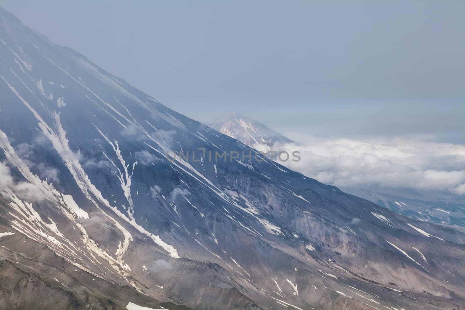 Mountains and volcanoes. Beautiful landscape of Kamchatka Peninsula: summer panoramic view of Mountain Range Vachkazhets, mountain lake and clouds in blue sky on sunny day. Eurasia, Russian Far East, Kamchatka Region.