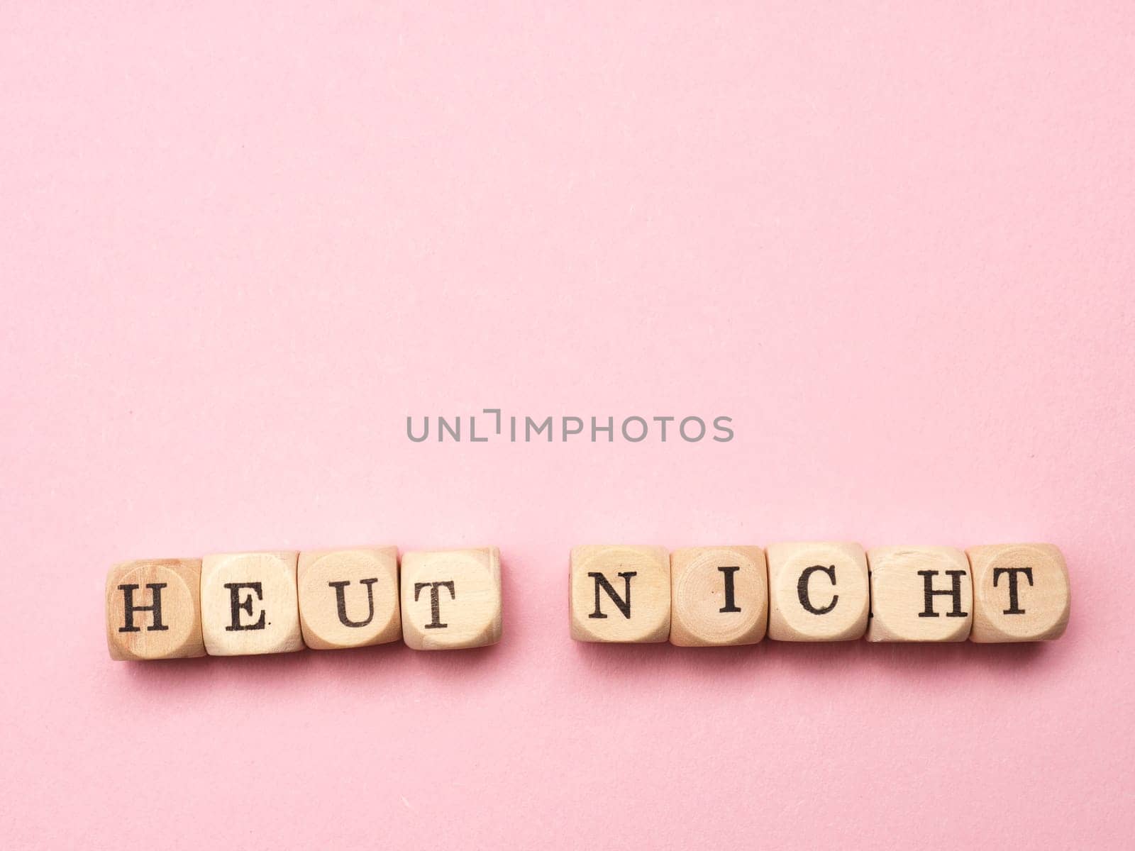 German words not today on wooden dices on a pink background with space for text or image