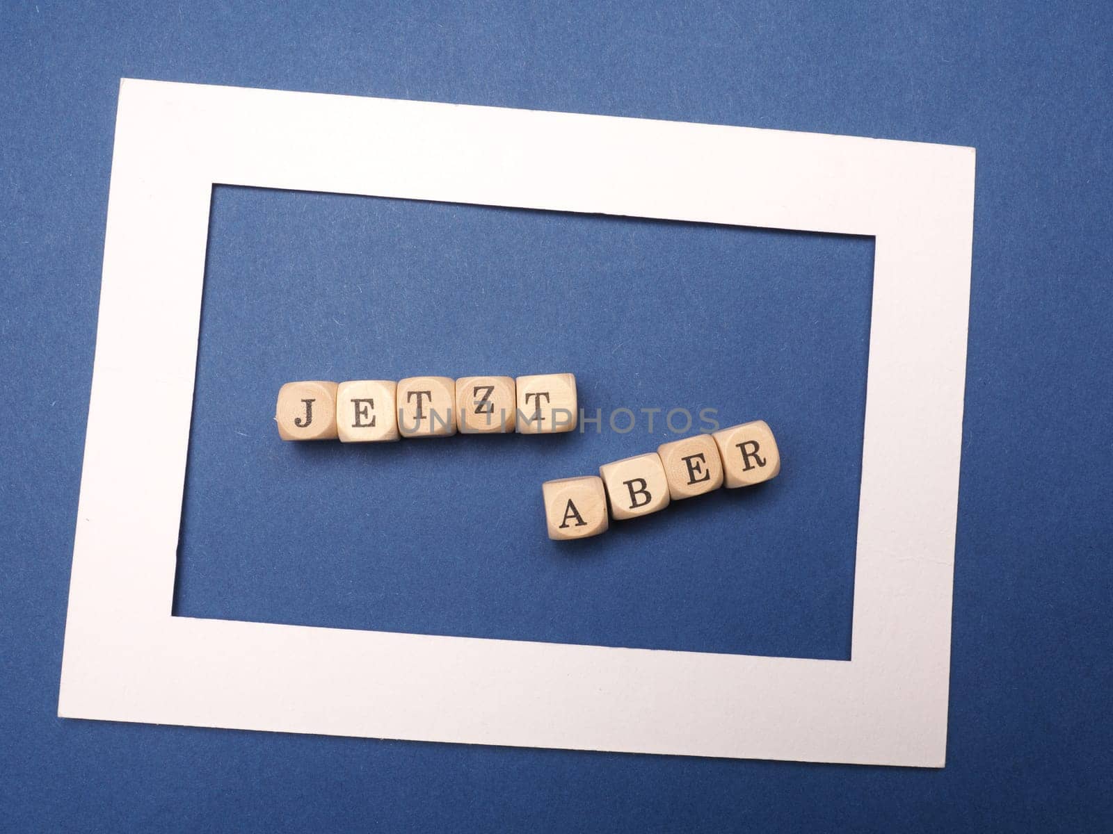 German words Start now on wooden dices on a blue background