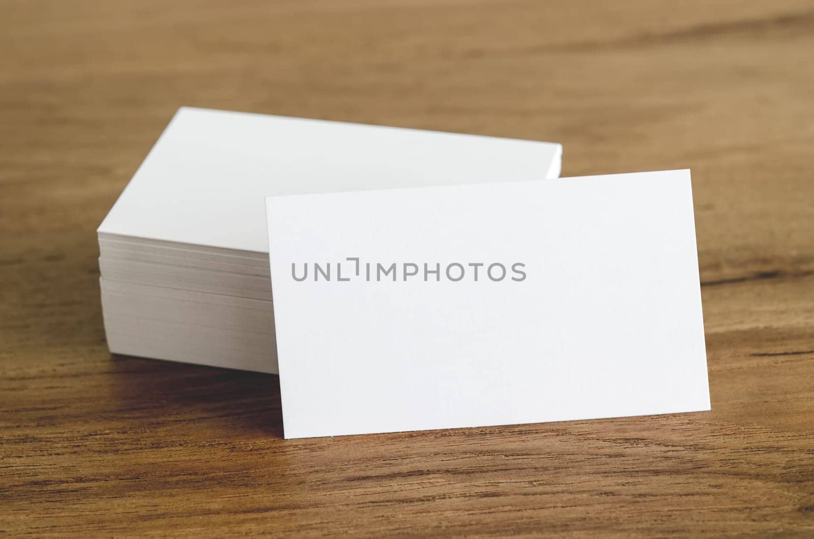 Blank business cards on brown wooden table.