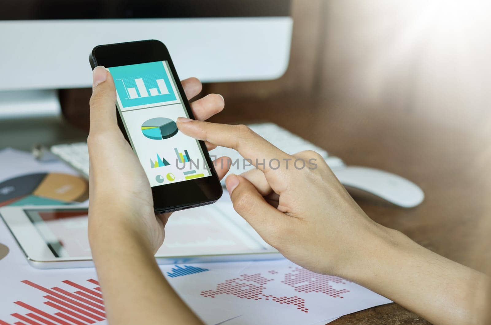 Business, office concept. Woman's hands using smart phone with financial document.
