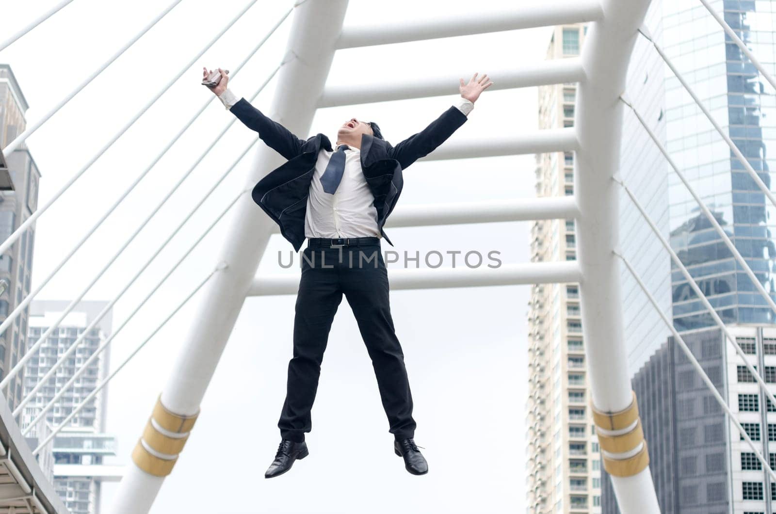 Success concept. Asian businessman jumping with happy moment and modern building background.