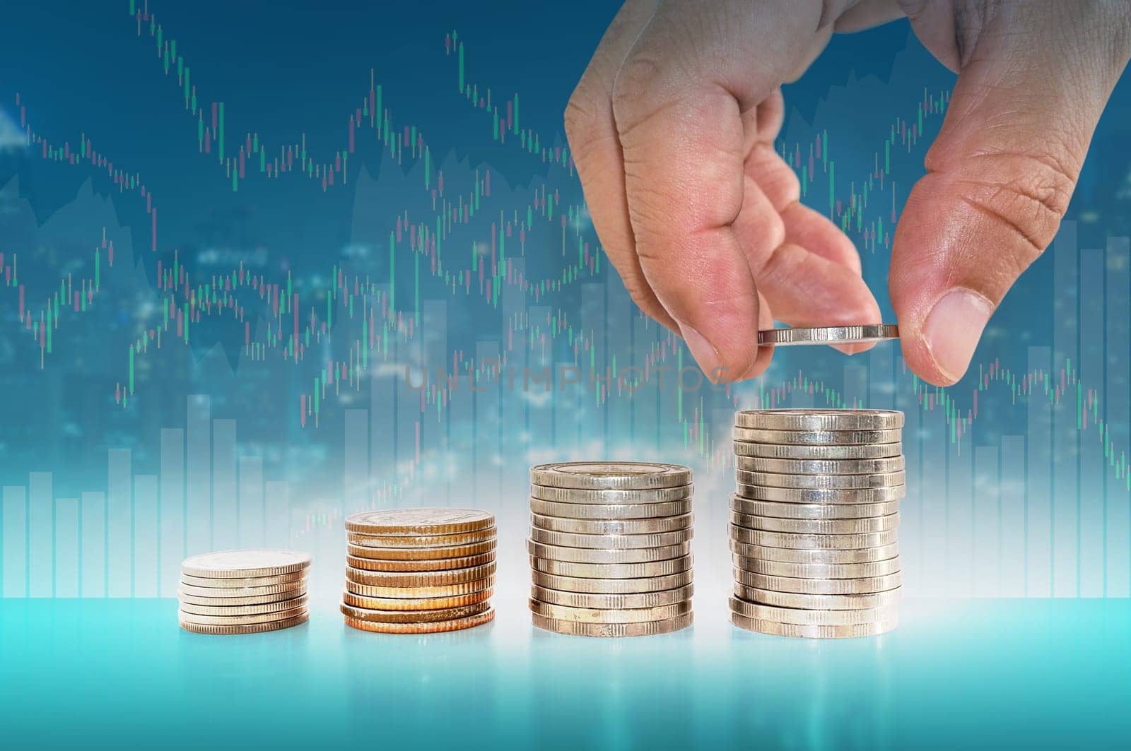Saving money concept. hand putting coin to stacks of coins with city scape financial graph stat business background.