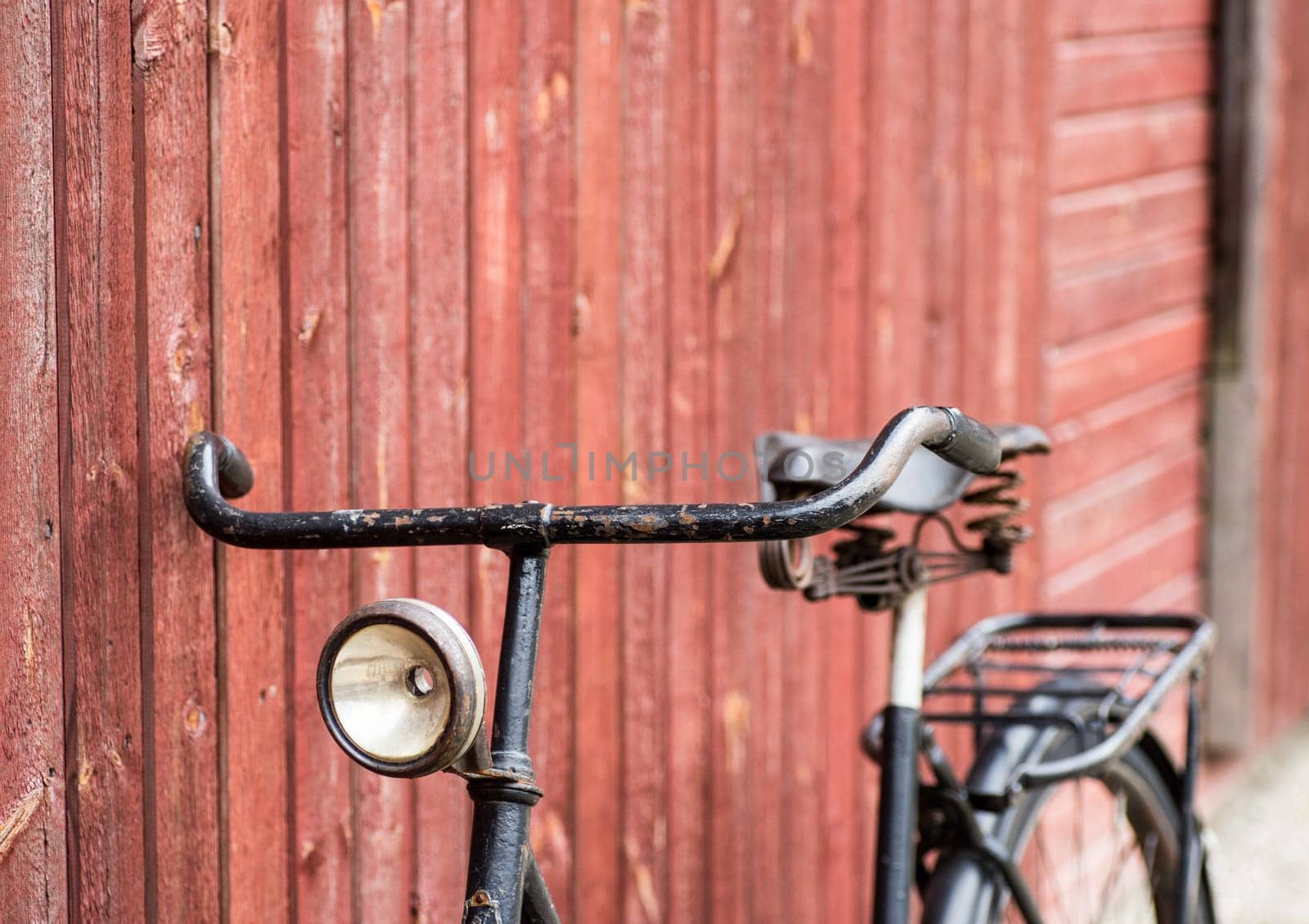 old retro antique black men's bicycle parked up of red wooden fence photographed from the side