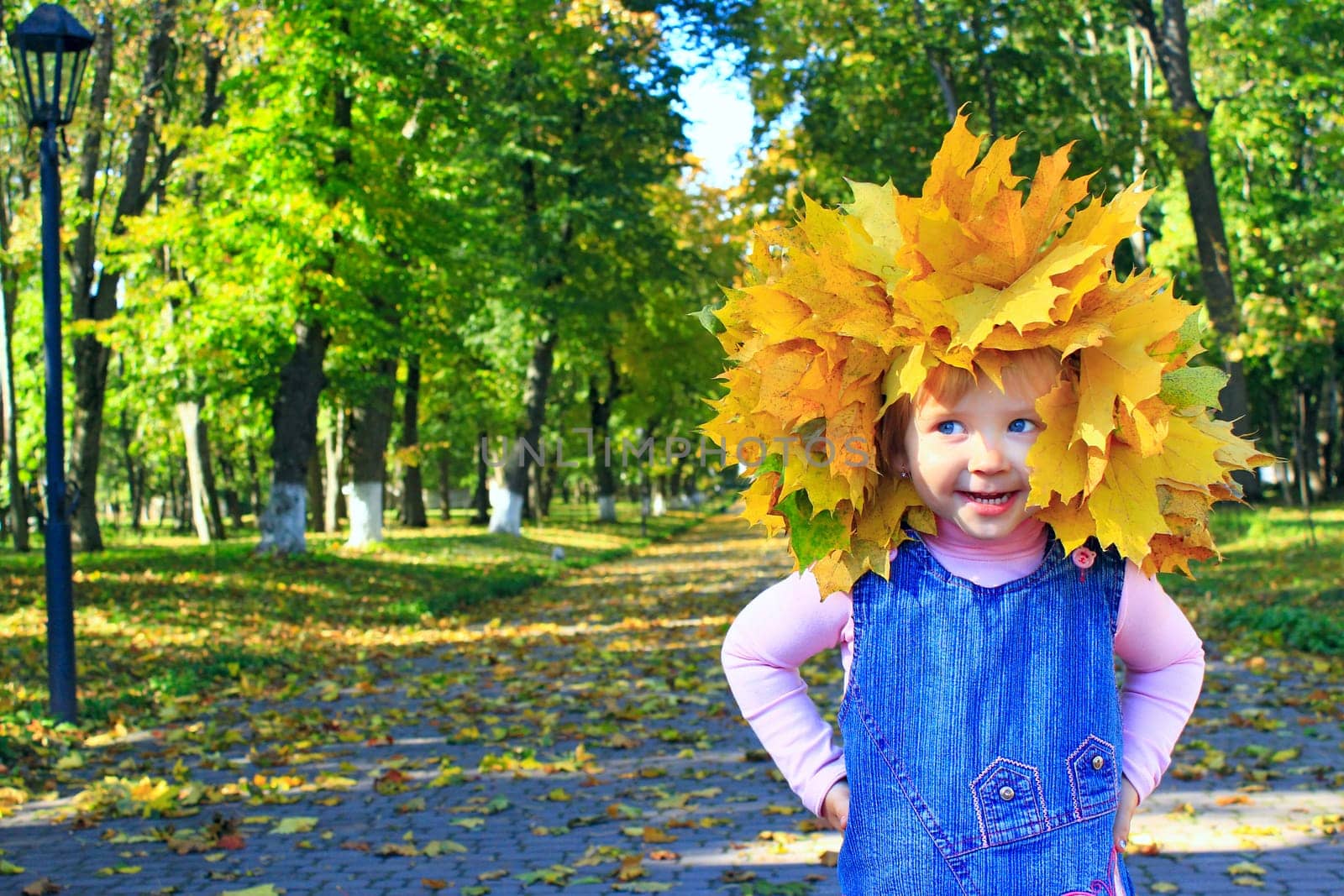 baby plays with yellow Autumn leaves in the park