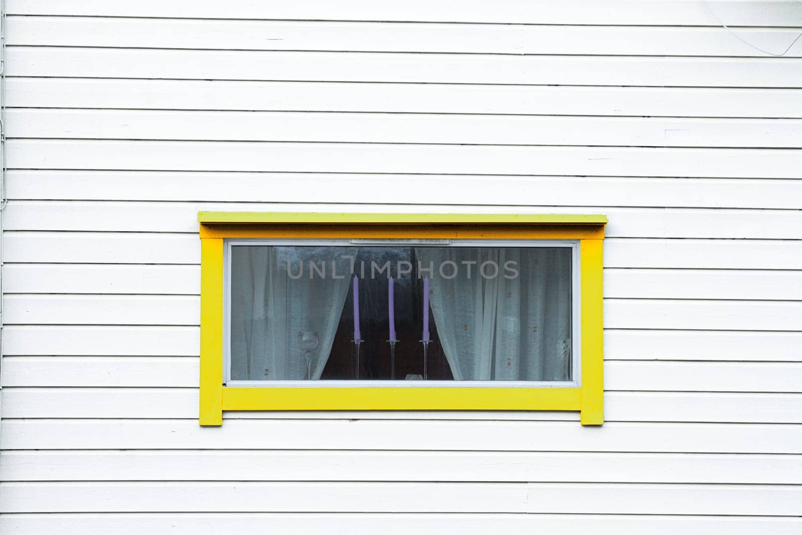 white wood wall yellow window curtain three candles