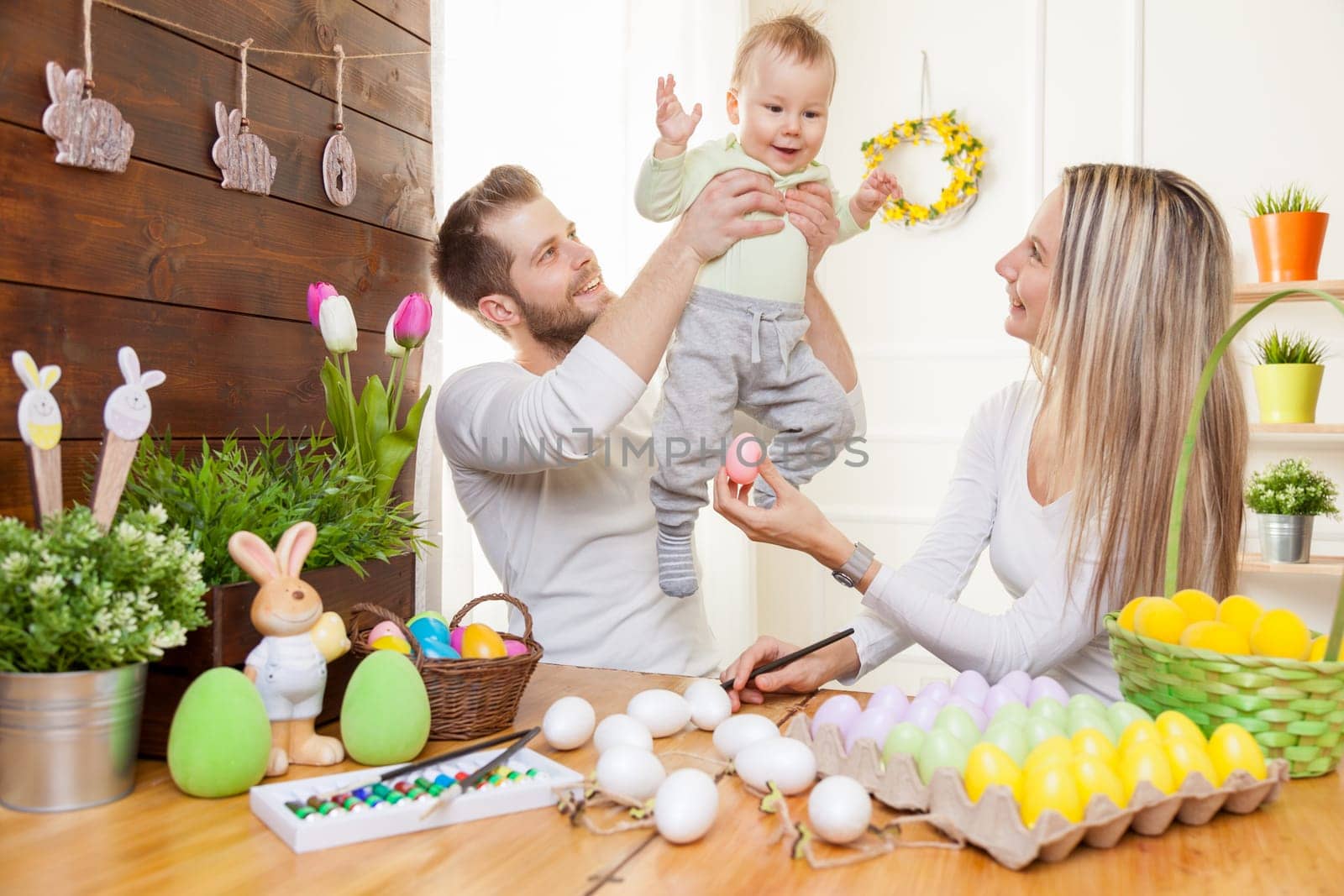Easter concept. Happy and loving mother and father preparing home decoration with their child for Easter holidays