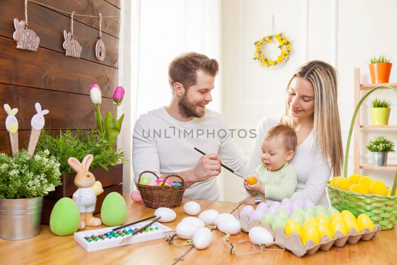 Easter concept. Happy and loving mother and father preparing home decoration with their child for Easter holidays