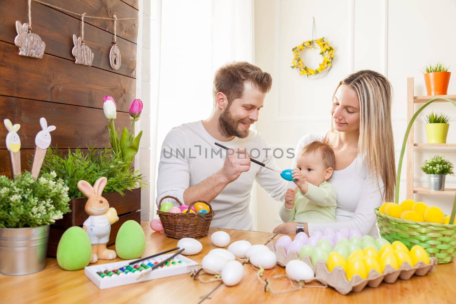 Easter concept. Happy and loving mother and father preparing home decoration with their child for Easter holidays