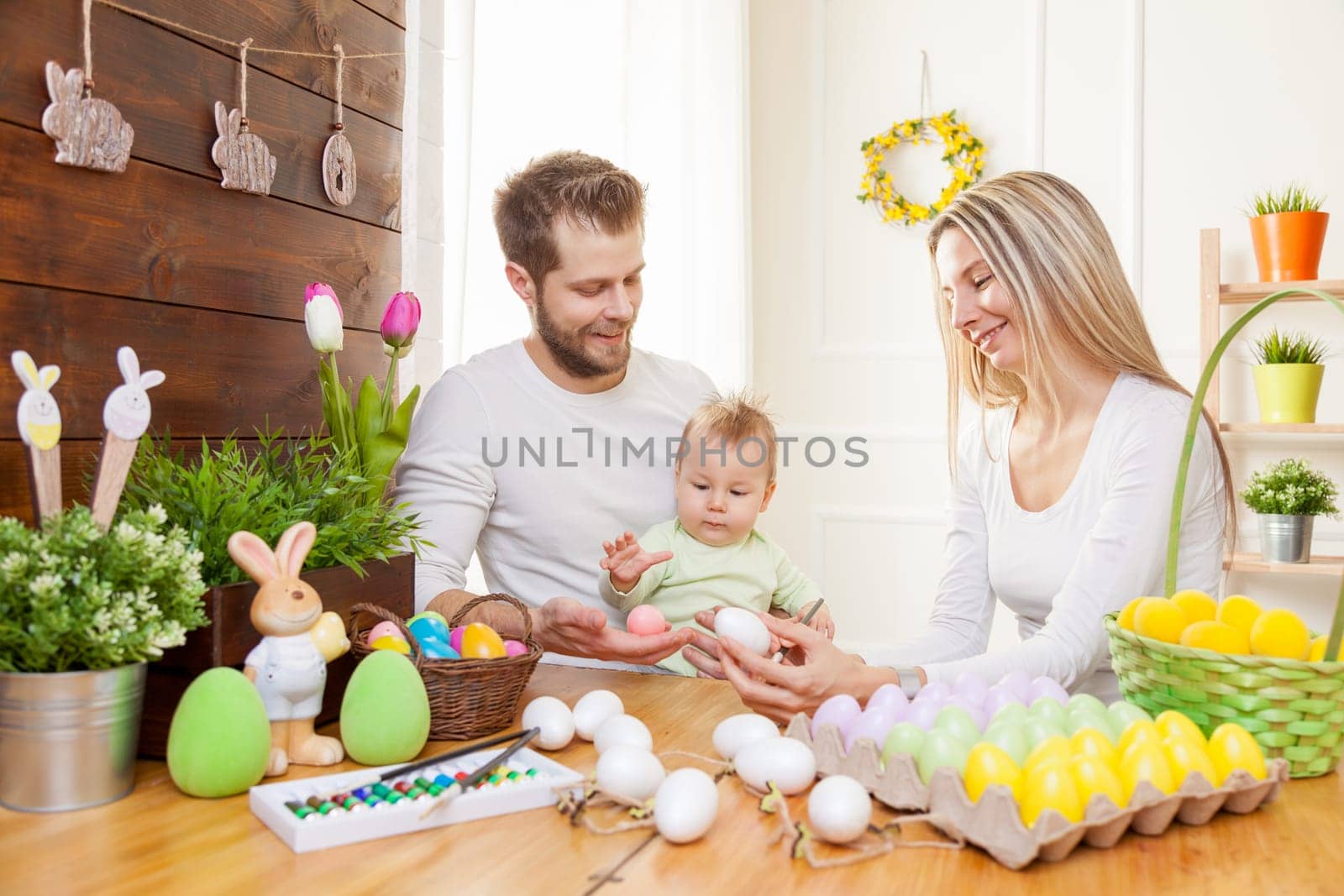 Easter concept. Happy and loving mother and father preparing home decoration with their child for Easter holidays