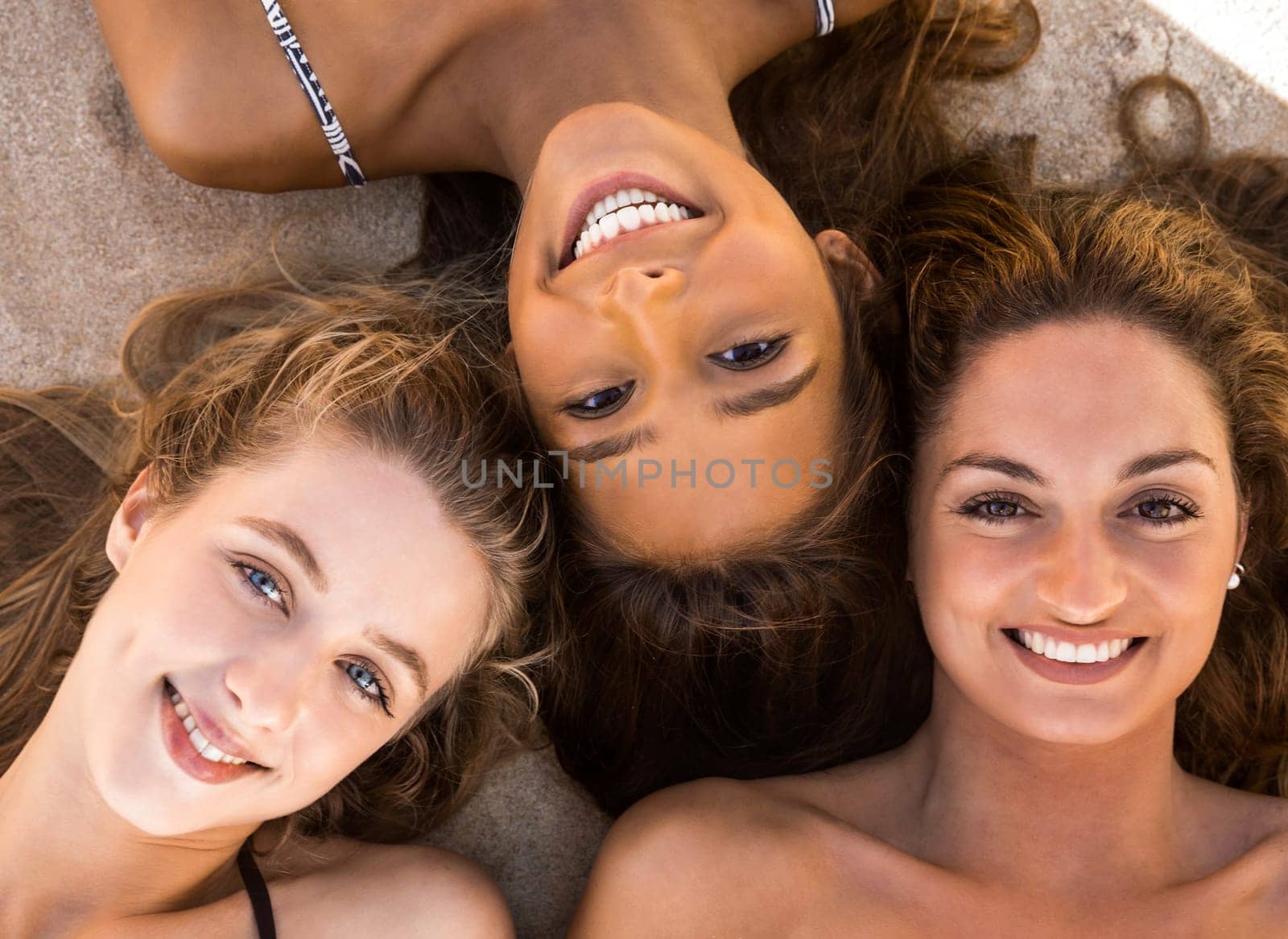 Three beautiful teenage embraced together on the beach