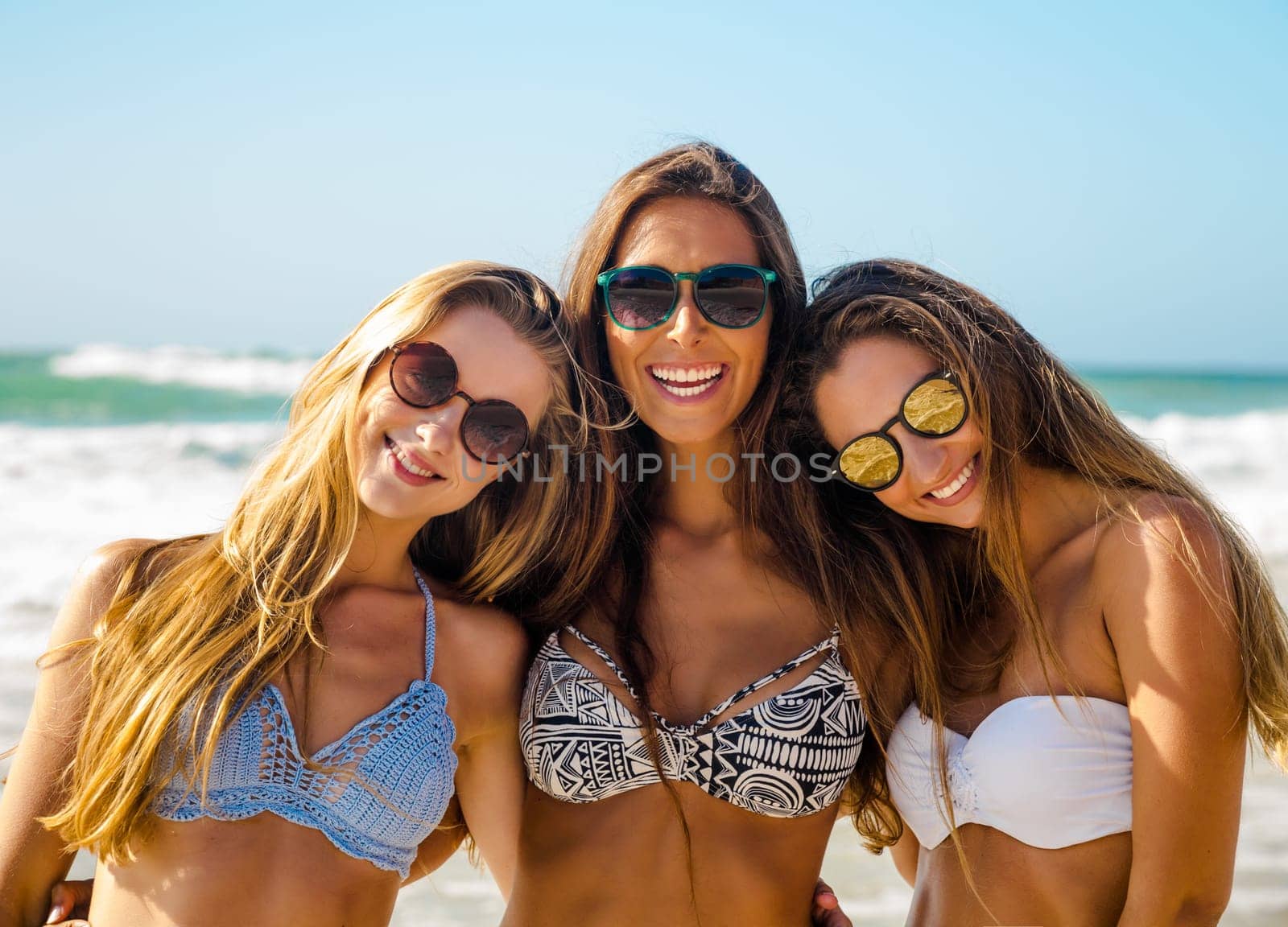 Beautiful teenage friends on the beach embraced together and looking back