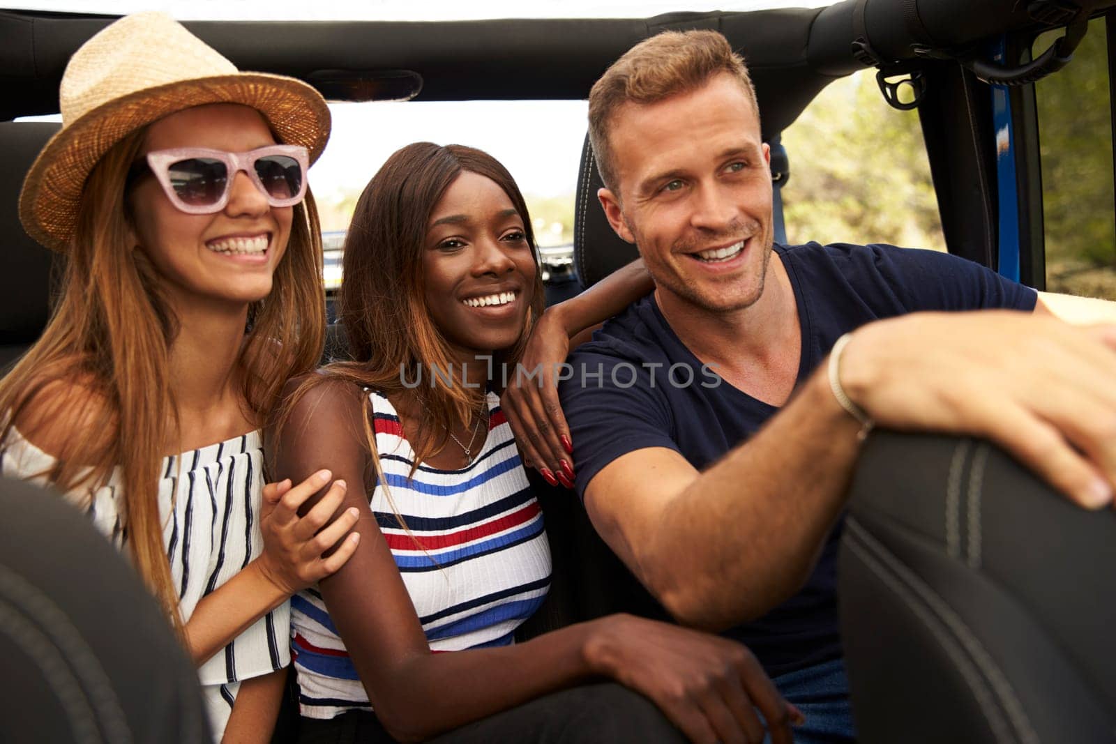 Group Of Friends Driving Open Top Car On Country Road
