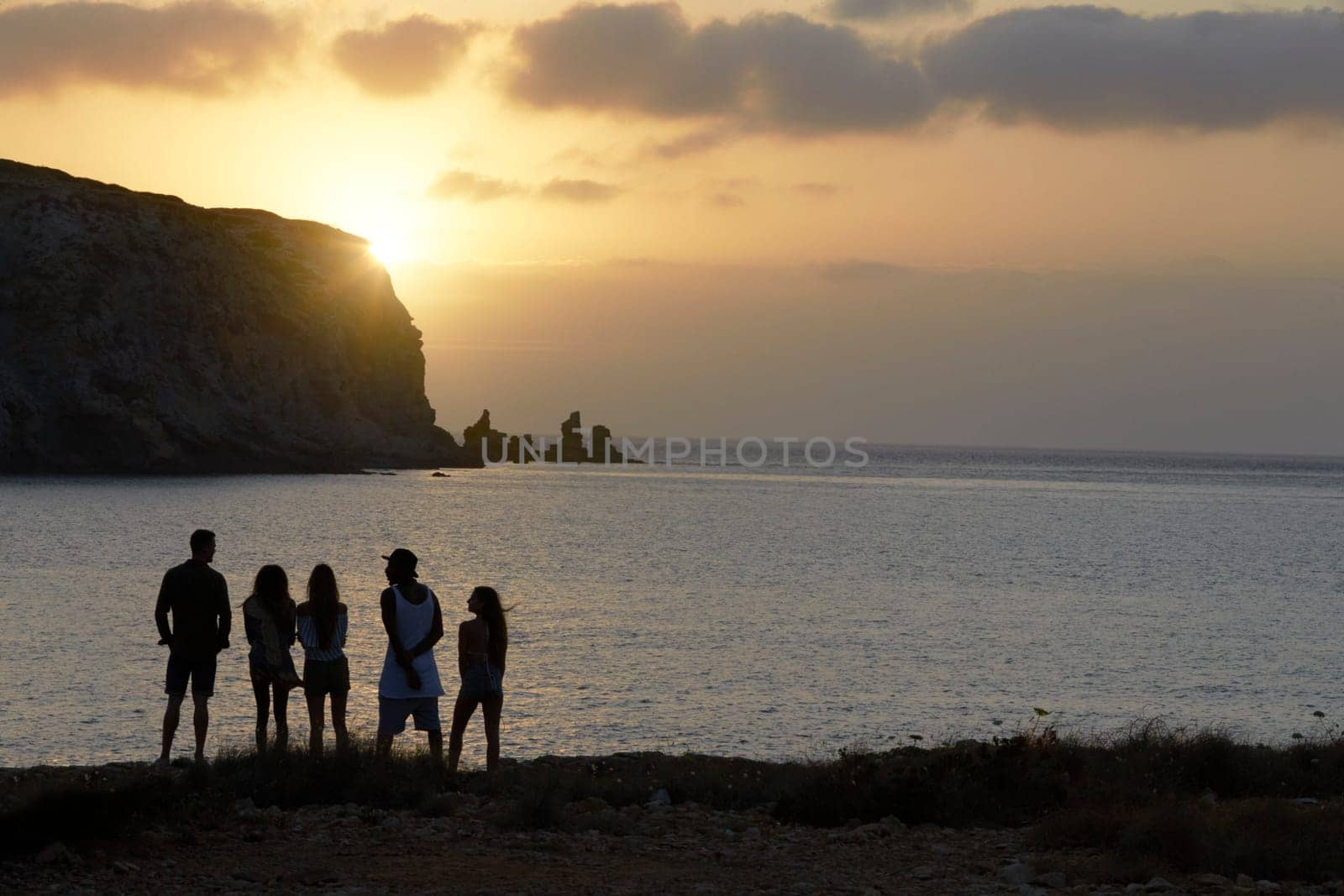 Rear View Of Friends Standing On Cliff Watching Sunset