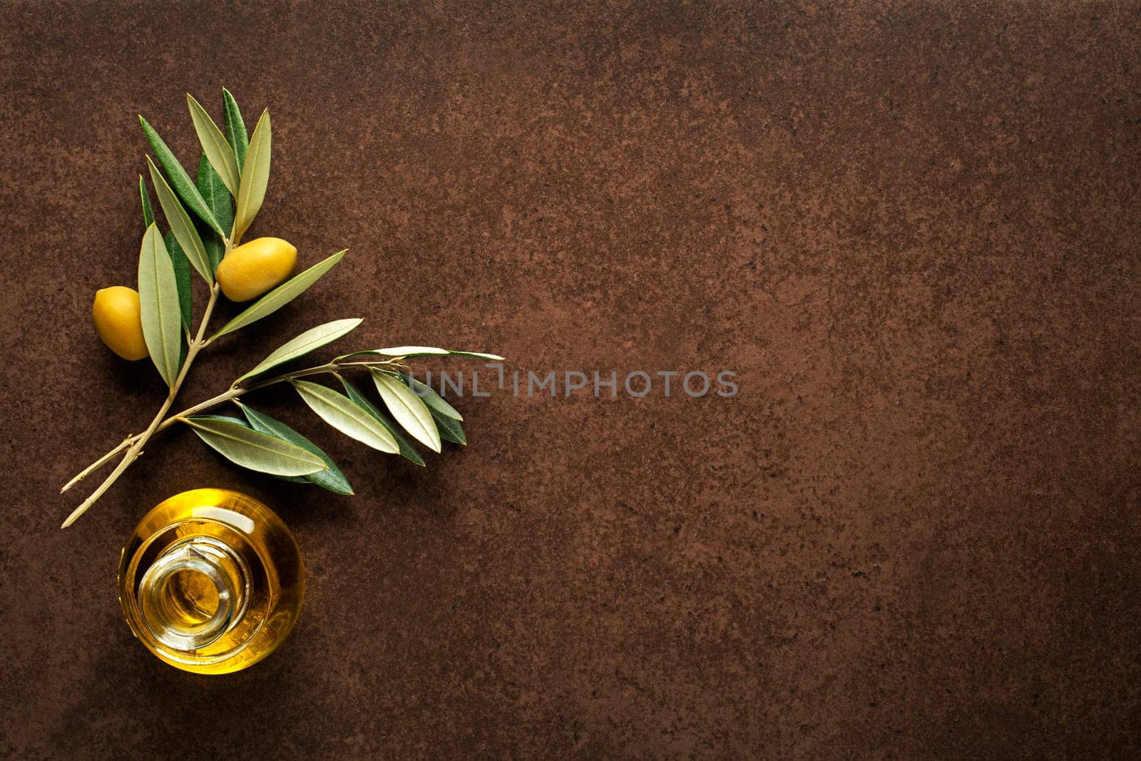 Olive oil and olive branch on brown table