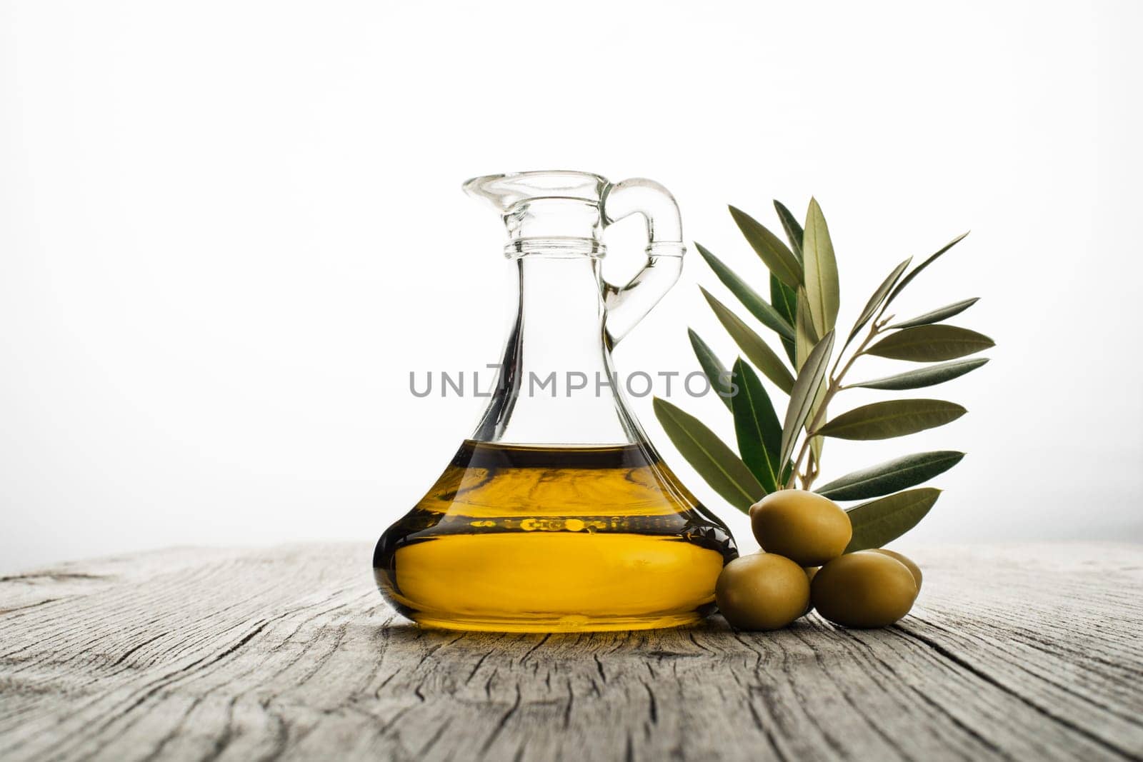 Olive oil and olive branch on wooden table