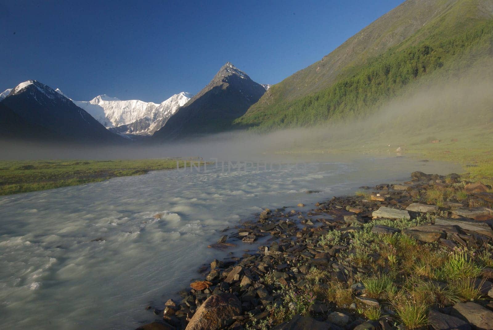 The mountain river in the mountains. Current through the gorge the river. Stones and rocky land near the river. Beautiful mountain landscape.