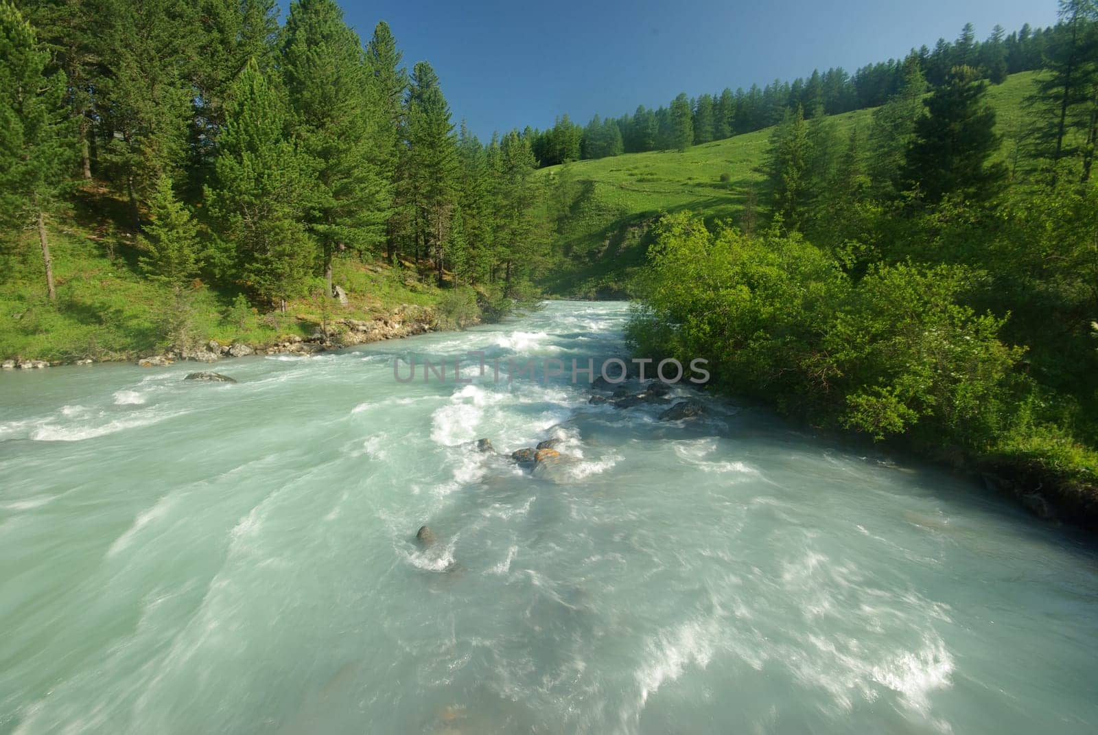 The mountain river in the mountains. Current through the gorge the river. Stones and rocky land near the river. Beautiful mountain landscape.