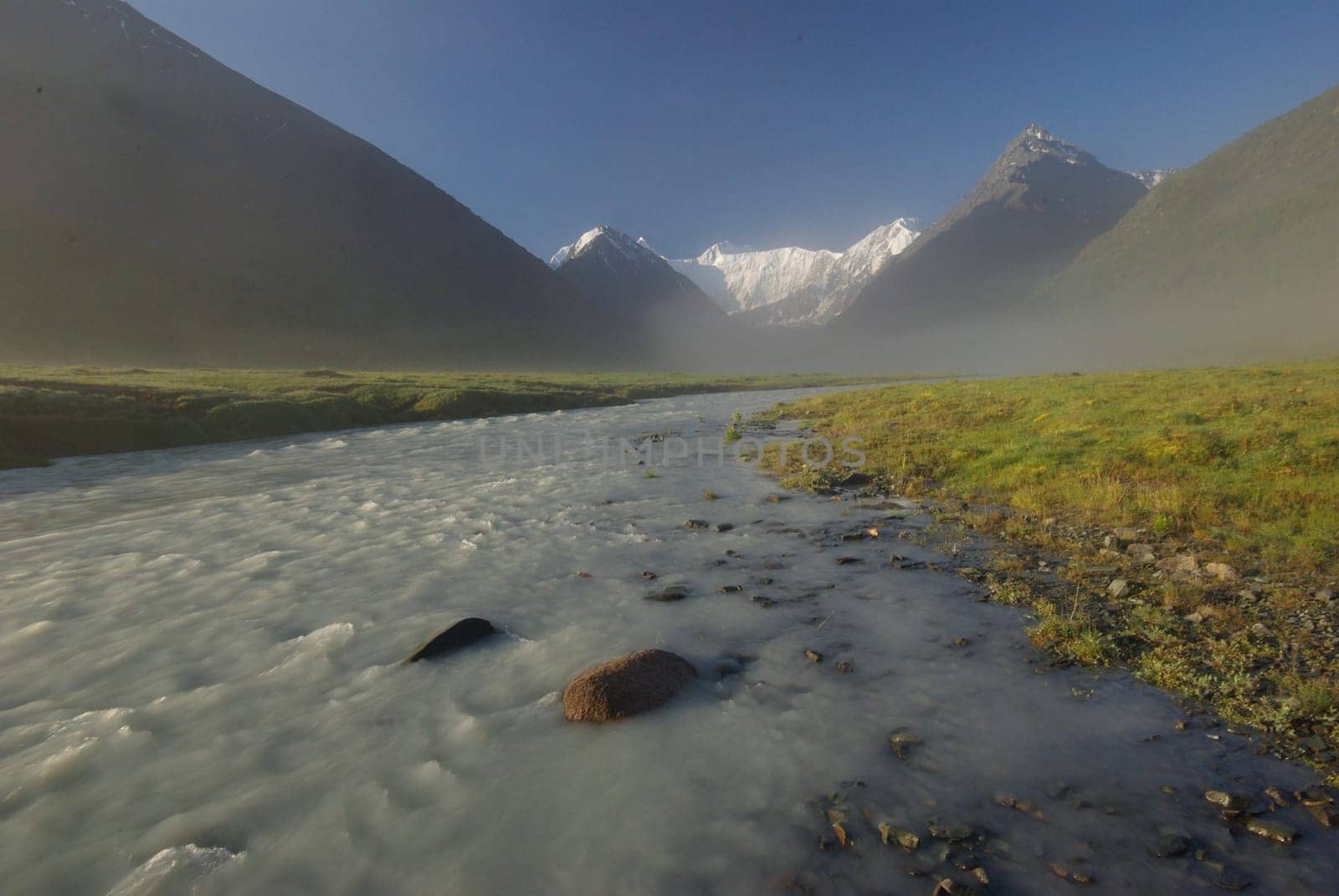 The mountain river in the mountains. Current through the gorge the river. Stones and rocky land near the river. Beautiful mountain landscape.