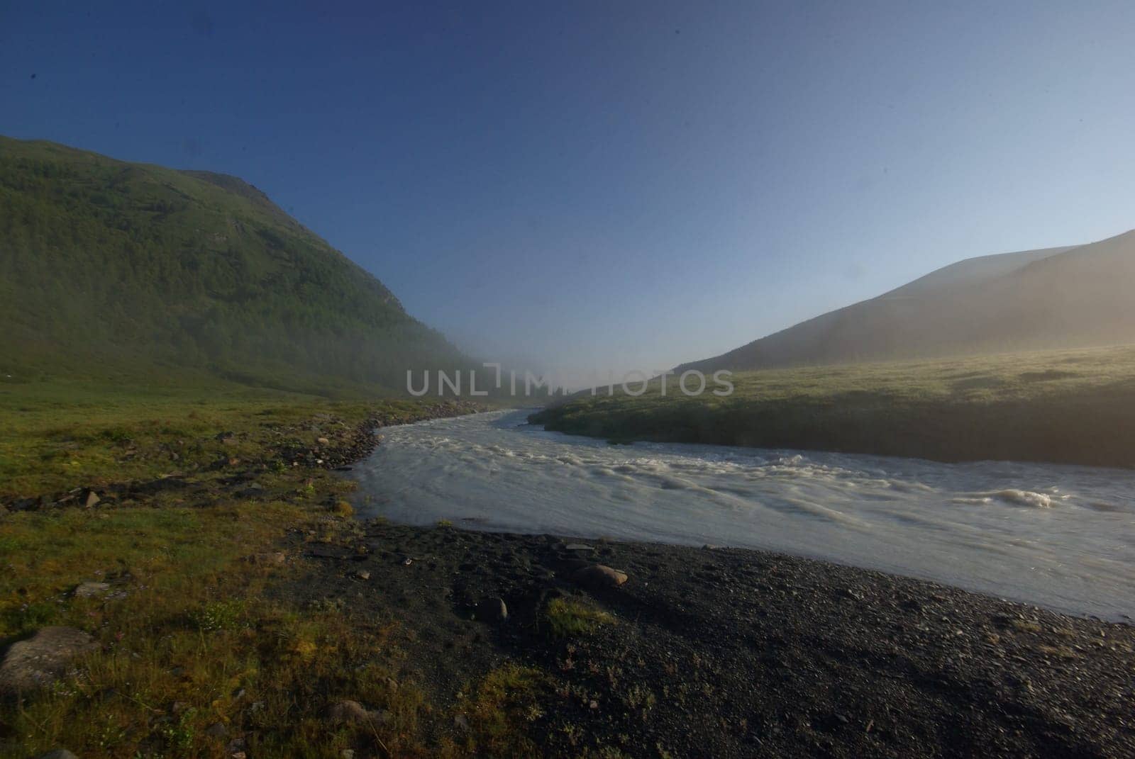 The mountain river in the mountains. Current through the gorge the river. Stones and rocky land near the river. Beautiful mountain landscape.