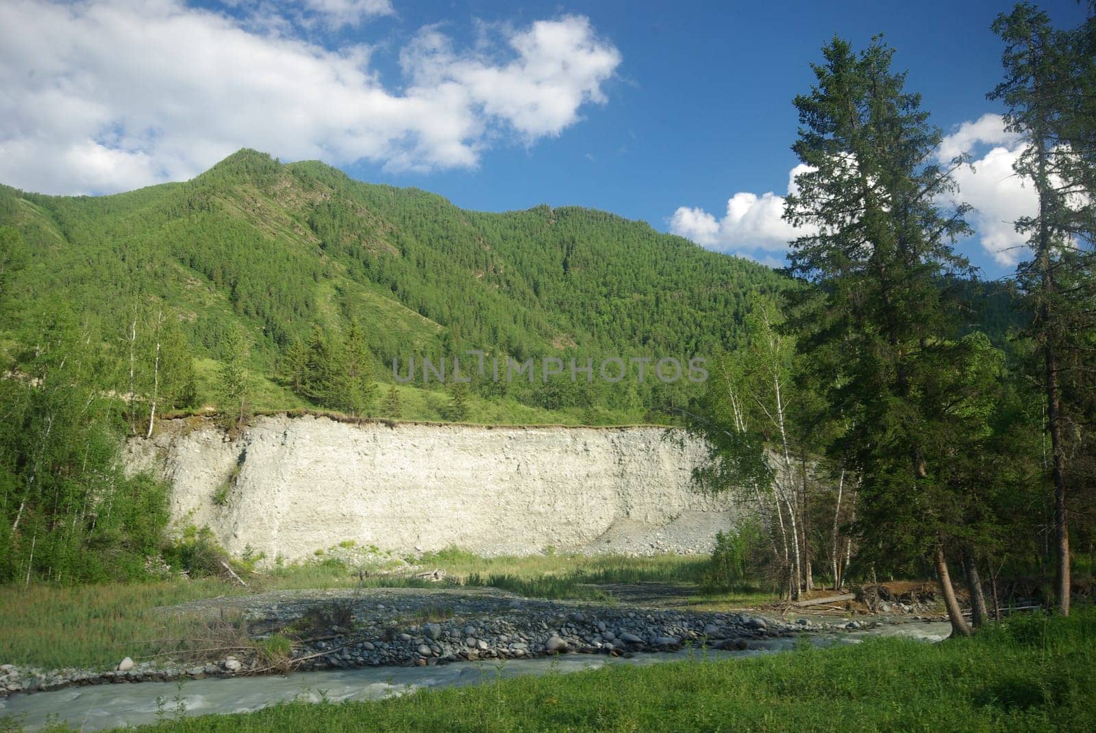 The mountain river in the mountains. Current through the gorge the river. Stones and rocky land near the river. Beautiful mountain landscape.