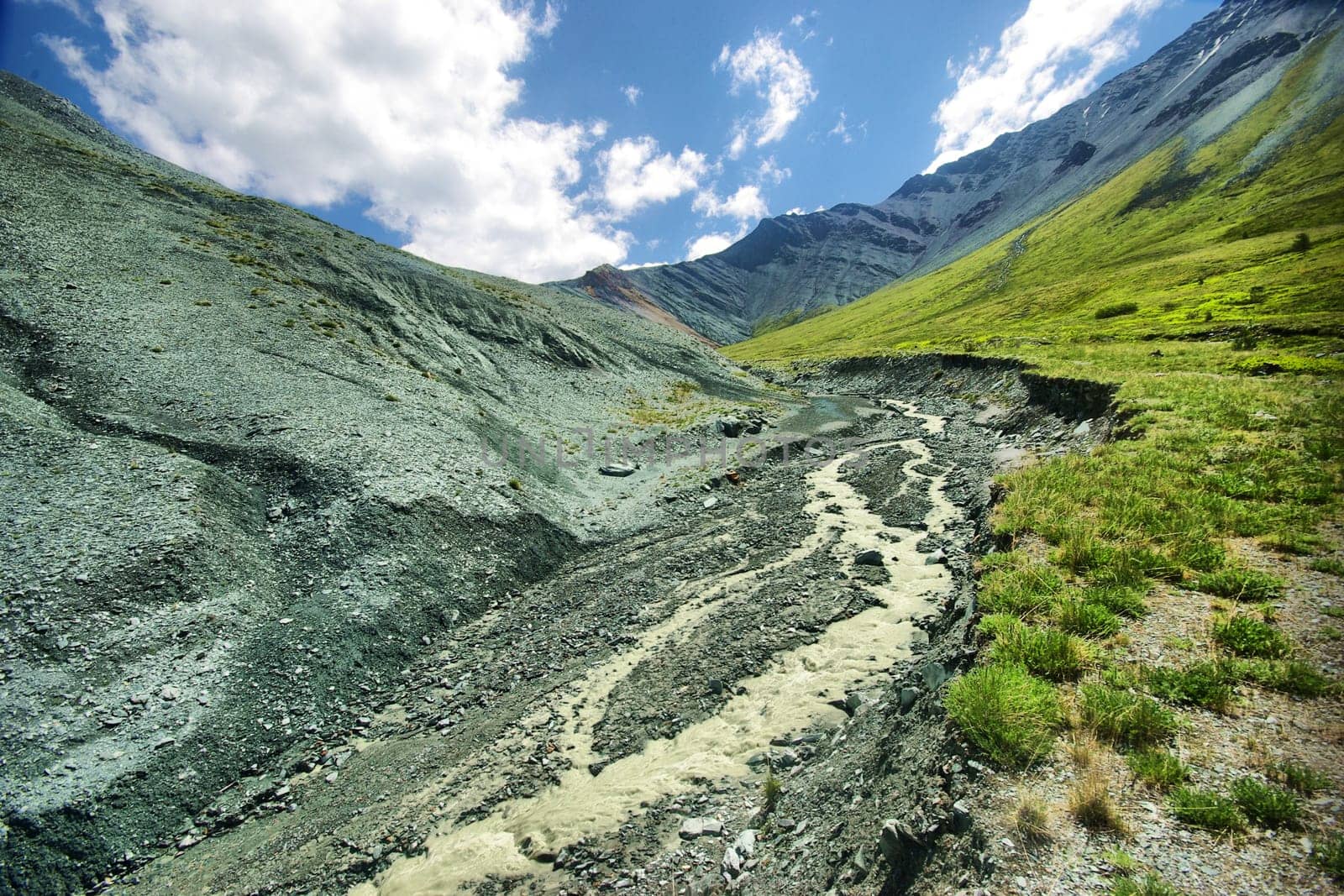 The mountain river in the mountains. Current through the gorge the river. Stones and rocky land near the river. Beautiful mountain landscape.
