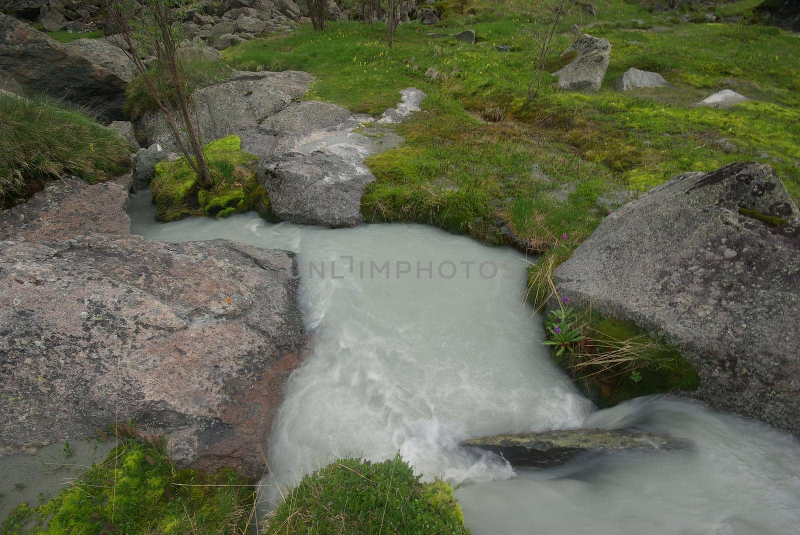 The mountain river in the mountains. Current through the gorge the river. Stones and rocky land near the river. Beautiful mountain landscape.