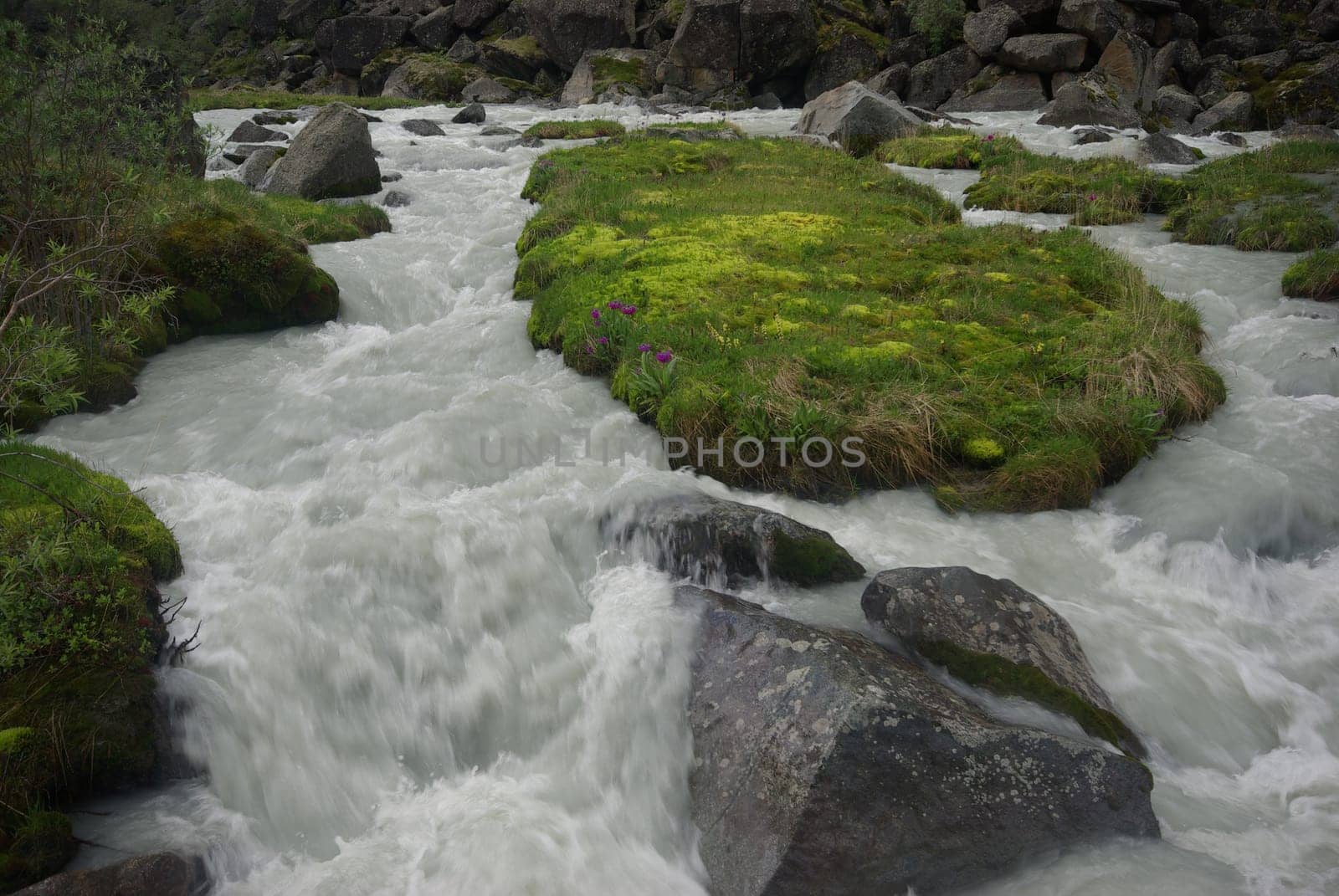 The mountain river in the mountains. Current through the gorge the river. Stones and rocky land near the river. Beautiful mountain landscape.