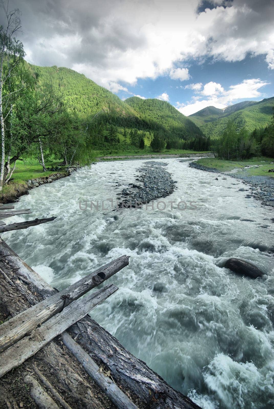 The mountain river in the mountains. Current through the gorge the river. Stones and rocky land near the river. Beautiful mountain landscape.