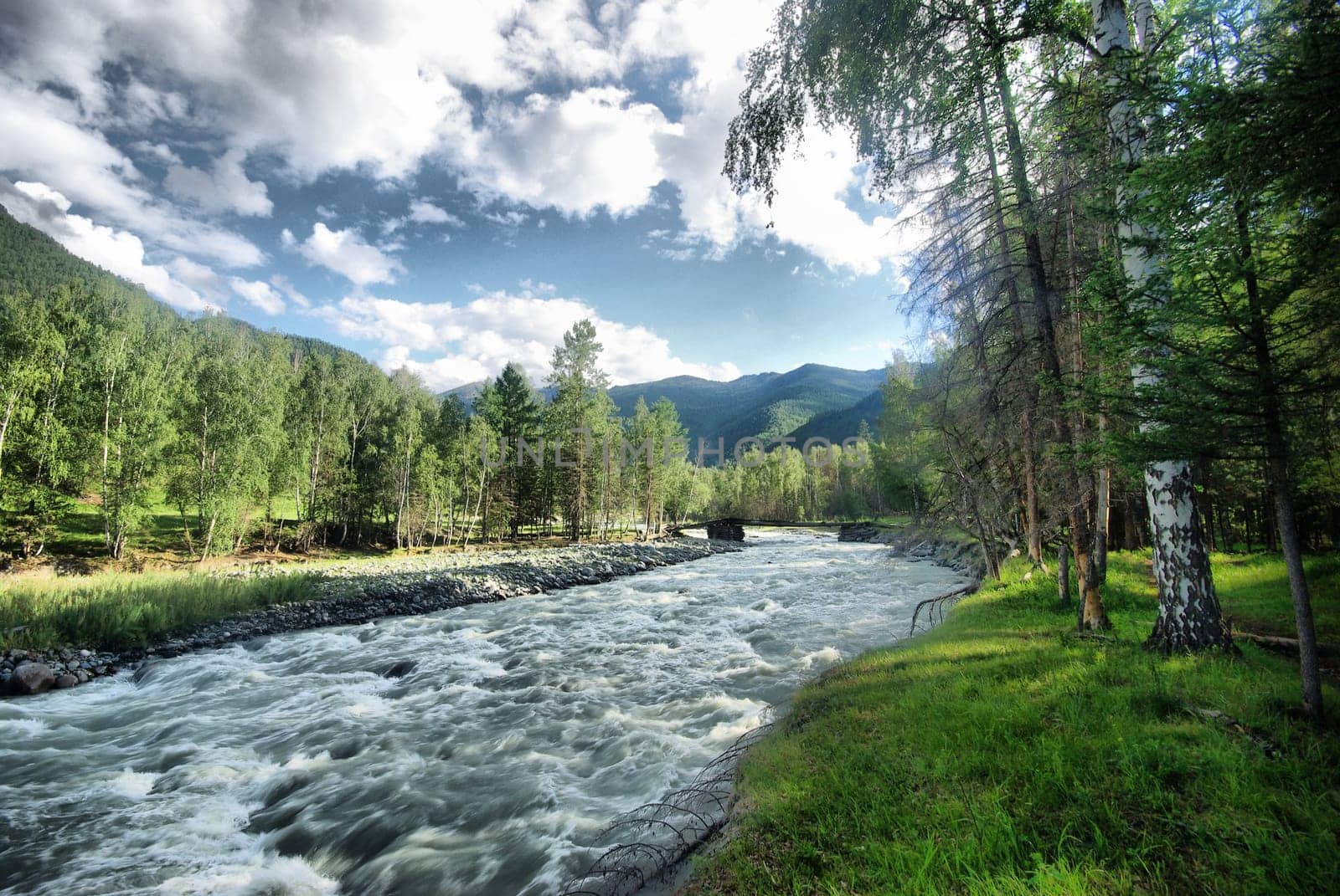 The mountain river in the mountains. Current through the gorge the river. Stones and rocky land near the river. Beautiful mountain landscape.