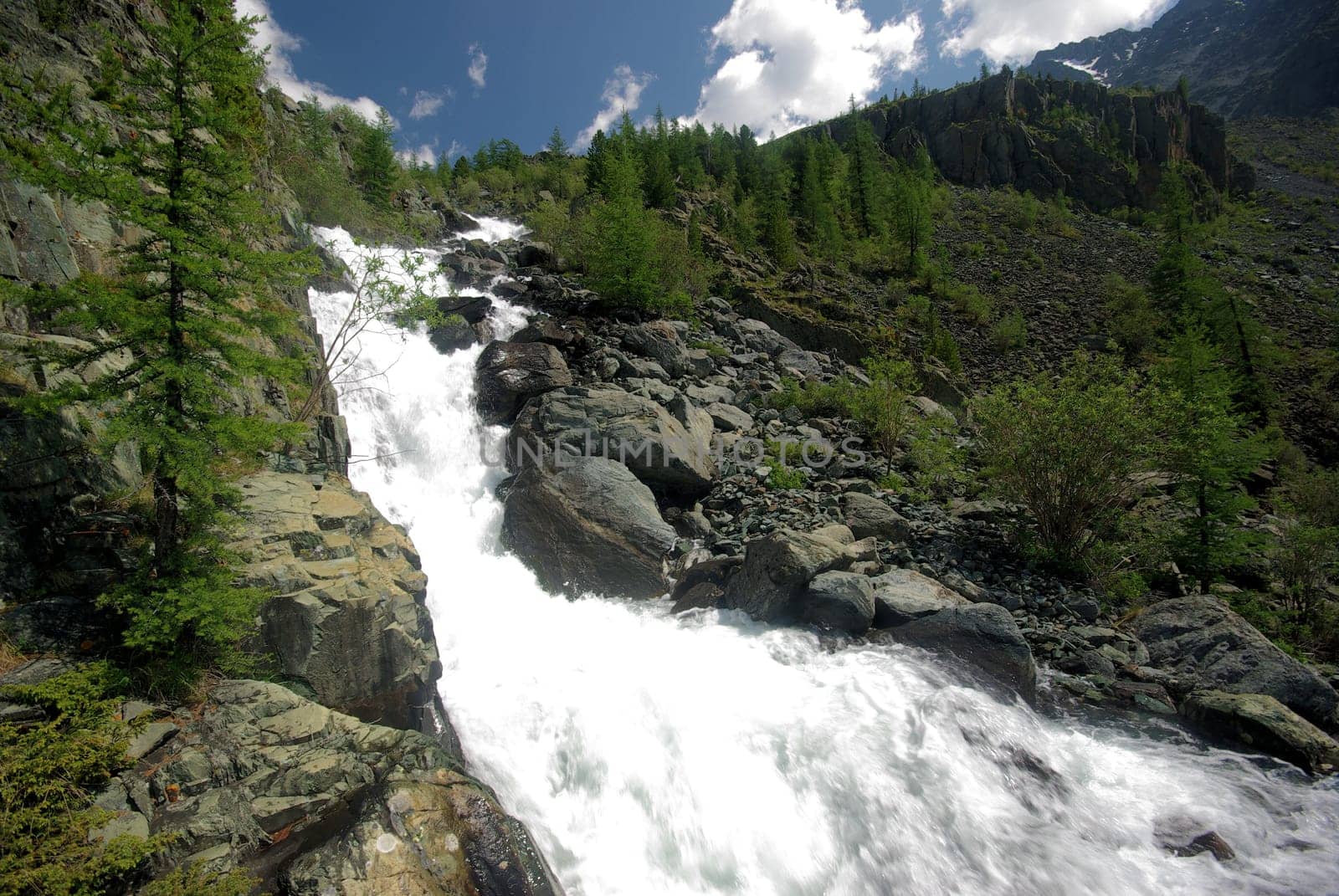 The mountain river in the mountains. Current through the gorge the river. Stones and rocky land near the river. Beautiful mountain landscape.