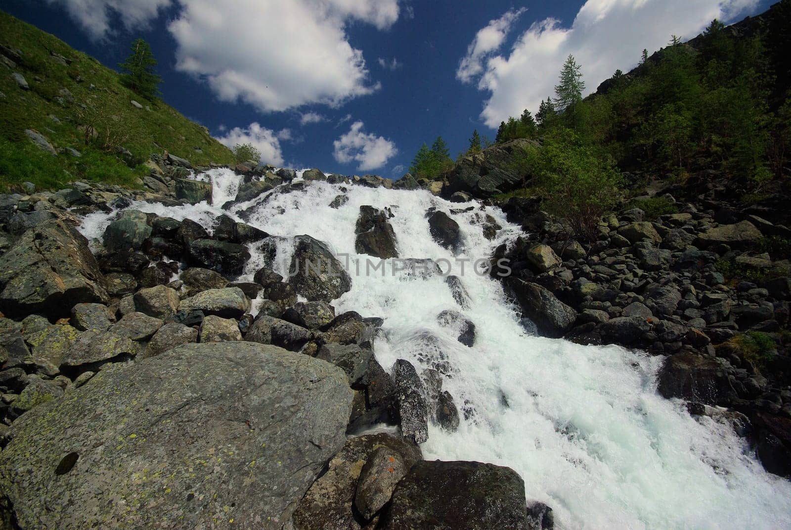 The mountain river in the mountains. Current through the gorge the river. Stones and rocky land near the river. Beautiful mountain landscape.