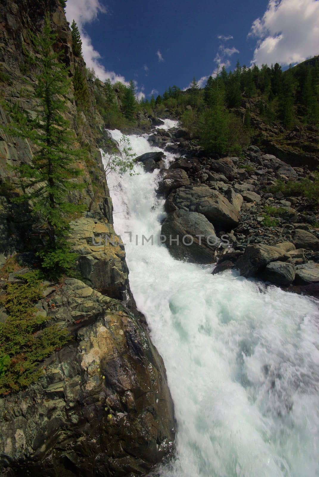 The mountain river in the mountains. Current through the gorge the river. Stones and rocky land near the river. Beautiful mountain landscape.