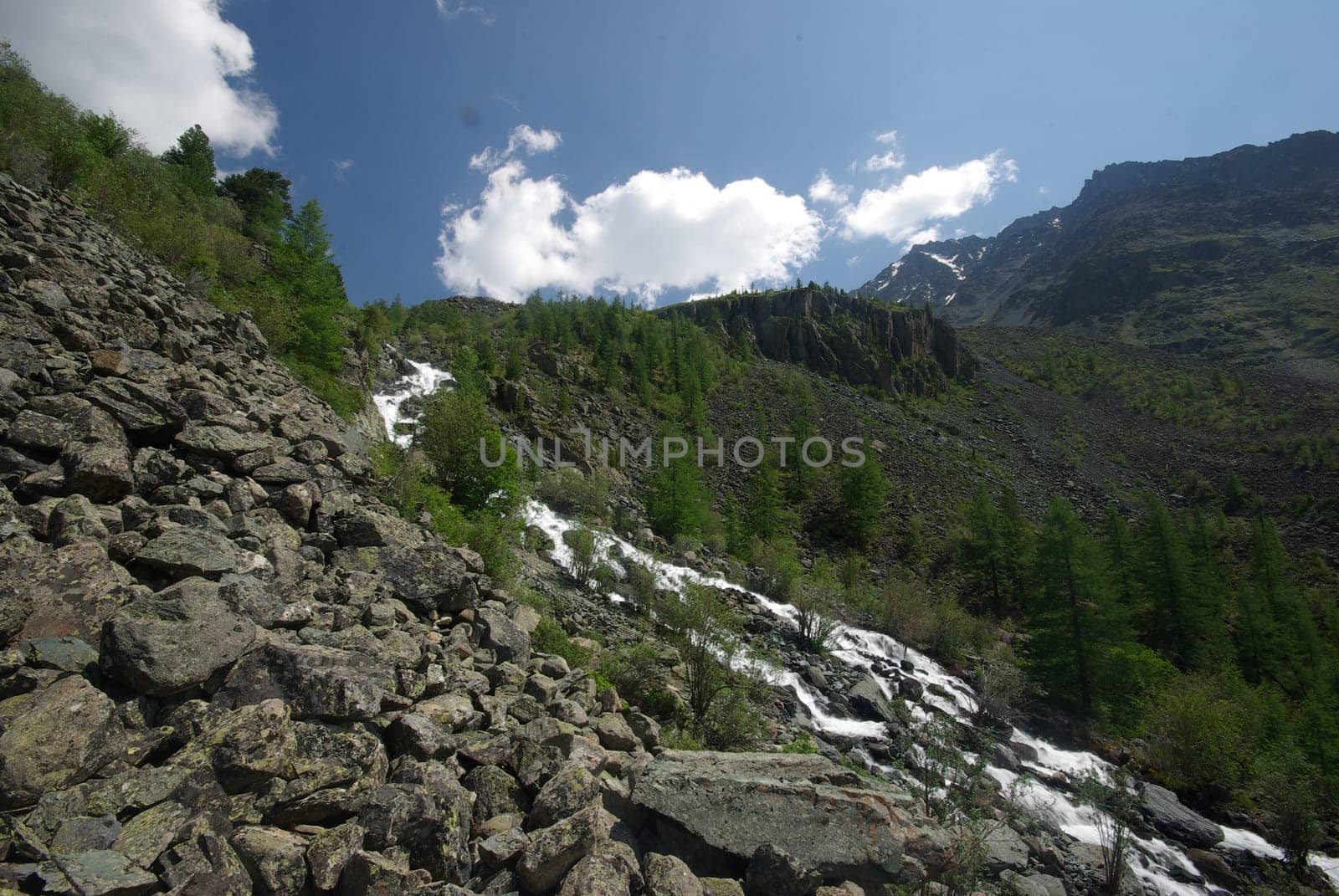The mountain river in the mountains. Current through the gorge the river. Stones and rocky land near the river. Beautiful mountain landscape.